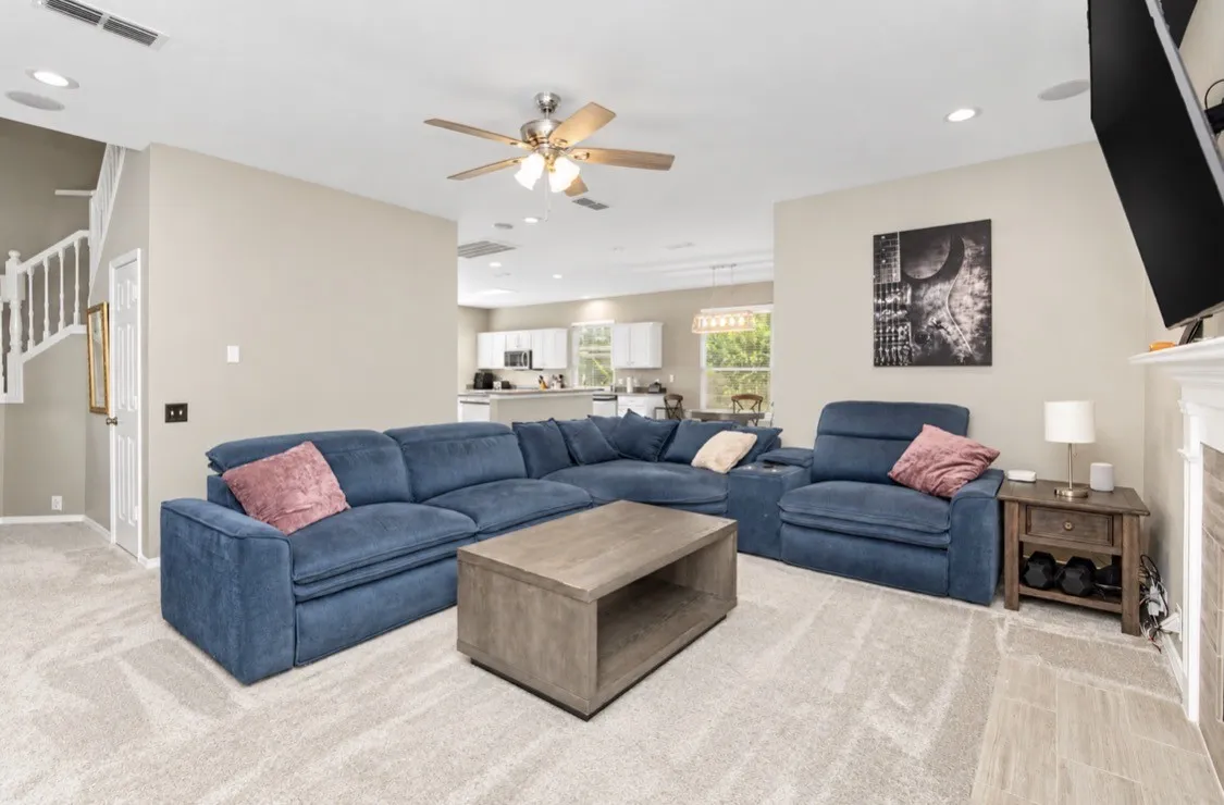 Carpeted living area with light-toned walls, a ceiling fan, and recessed lighting