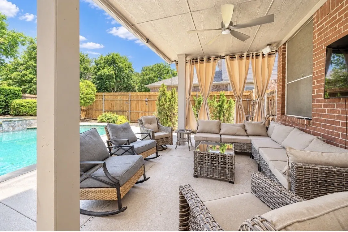 Covered patio featuring a ceiling fan, recessed lighting, privacy drapes, and a brick exterior wall