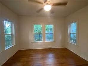 Empty room featuring healthy amount of natural light, wood finished floors, and ceiling fan