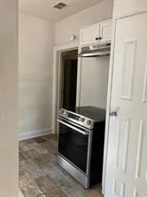 Kitchen with stainless steel range with electric cooktop, white cabinetry, and brick patterned floors