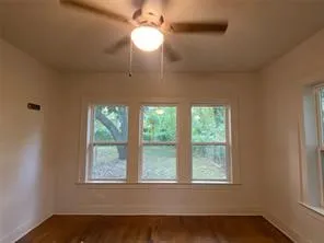 Unfurnished room featuring plenty of natural light, ceiling fan, and dark wood-style flooring