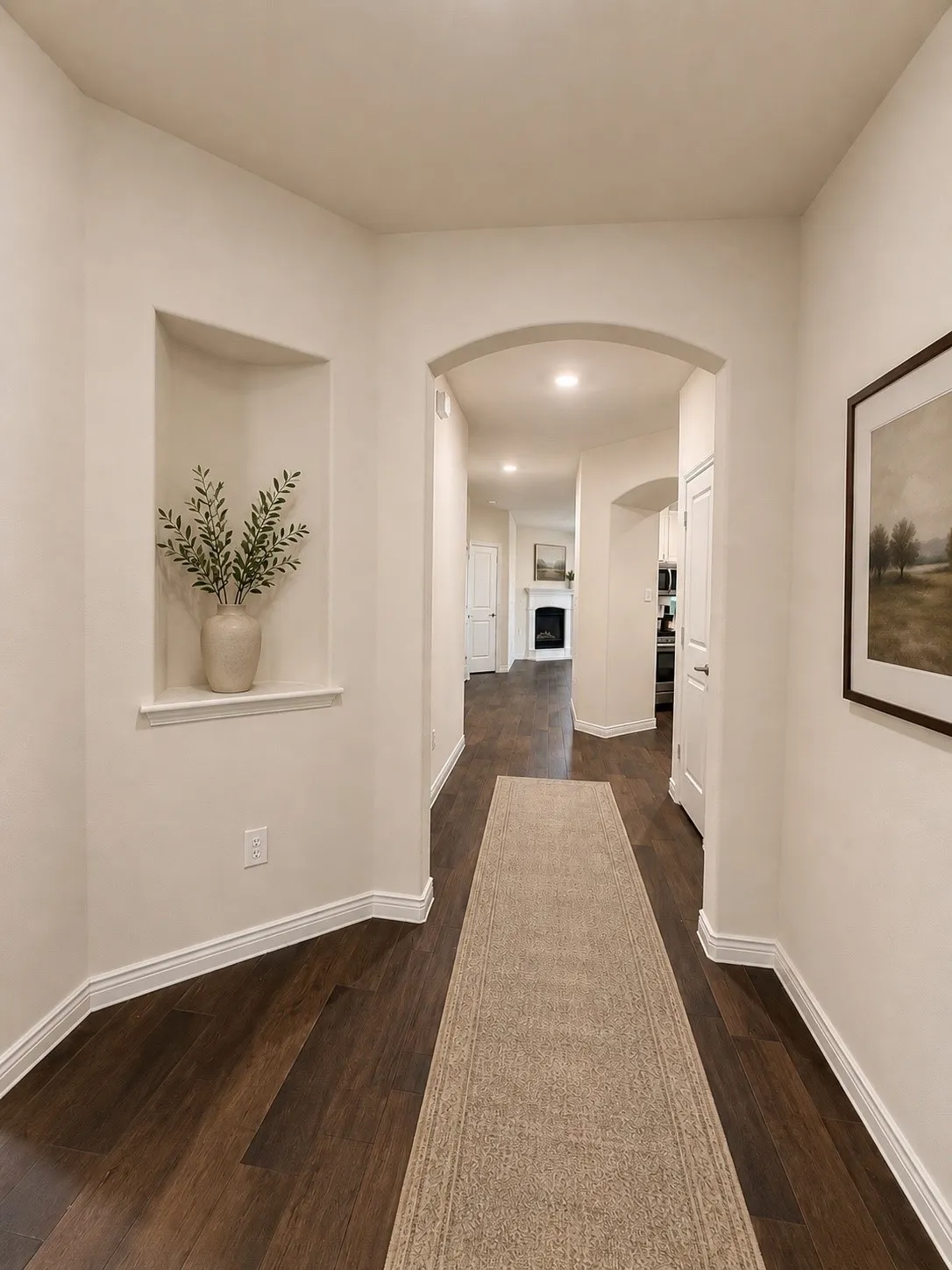 Wood-finish flooring throughout, featuring an arched entryway, recessed lighting, and a built-in wall niche