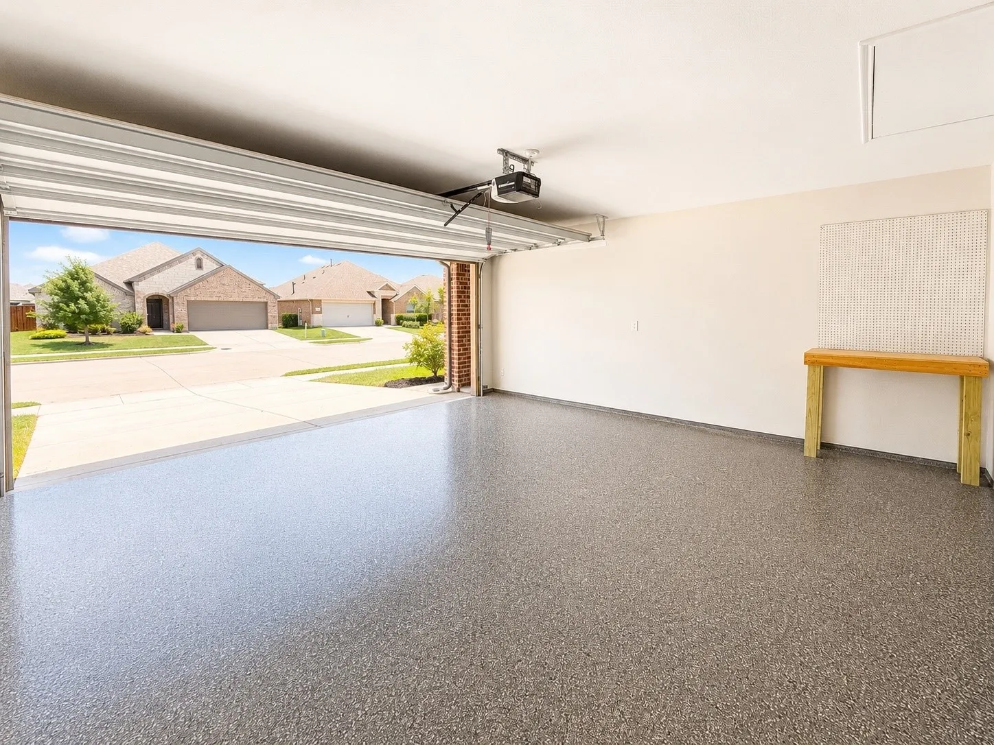 Garage featuring a wide overhead door, finished concrete flooring, and a remote-controlled opener