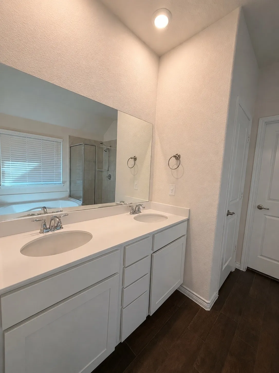 Dual vanity with white cabinetry, integrated sinks, chrome fixtures, and a spacious mirror