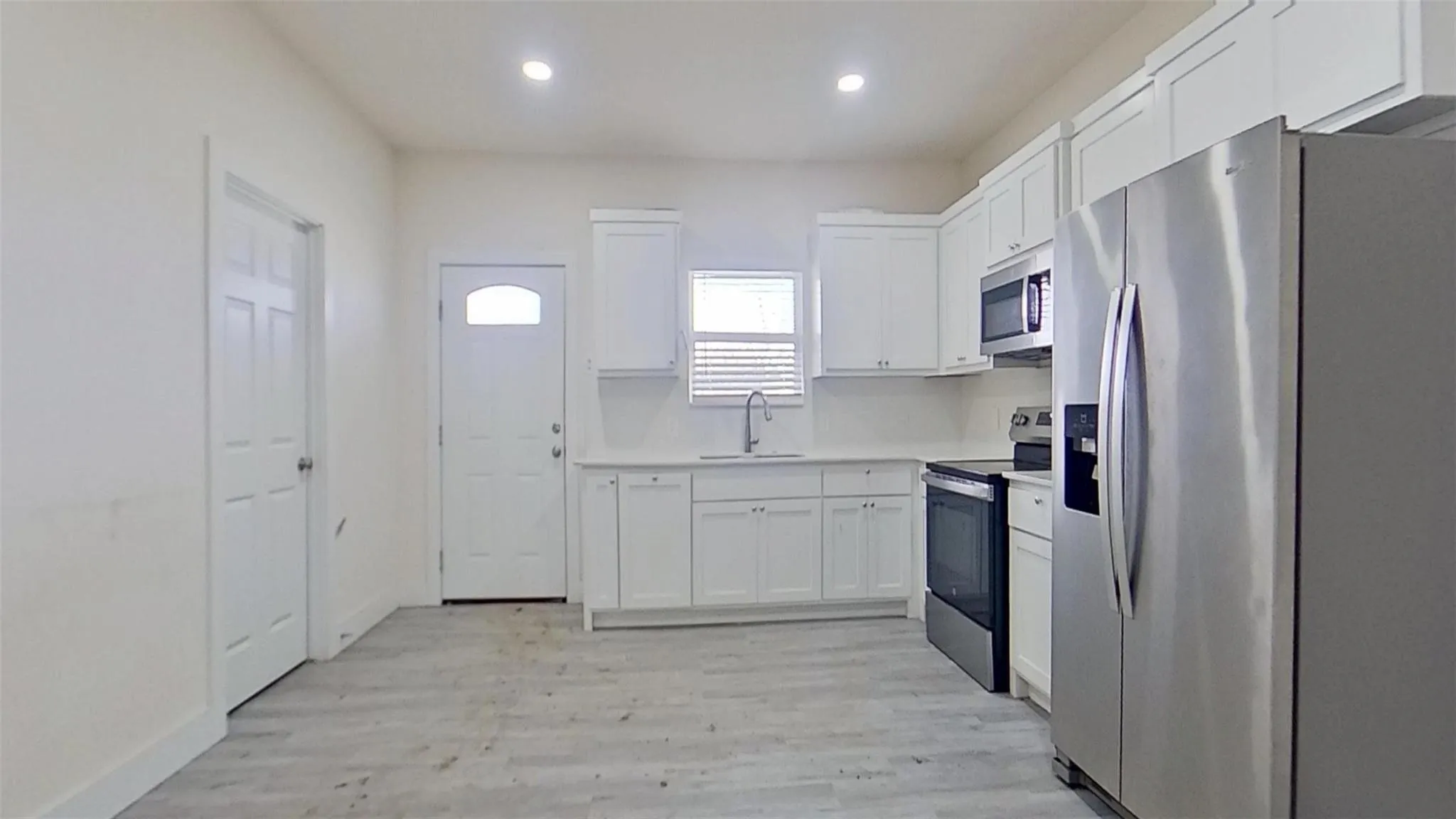 Kitchen featuring white cabinetry, light-toned countertops, a stainless steel refrigerator, and recessed lighting