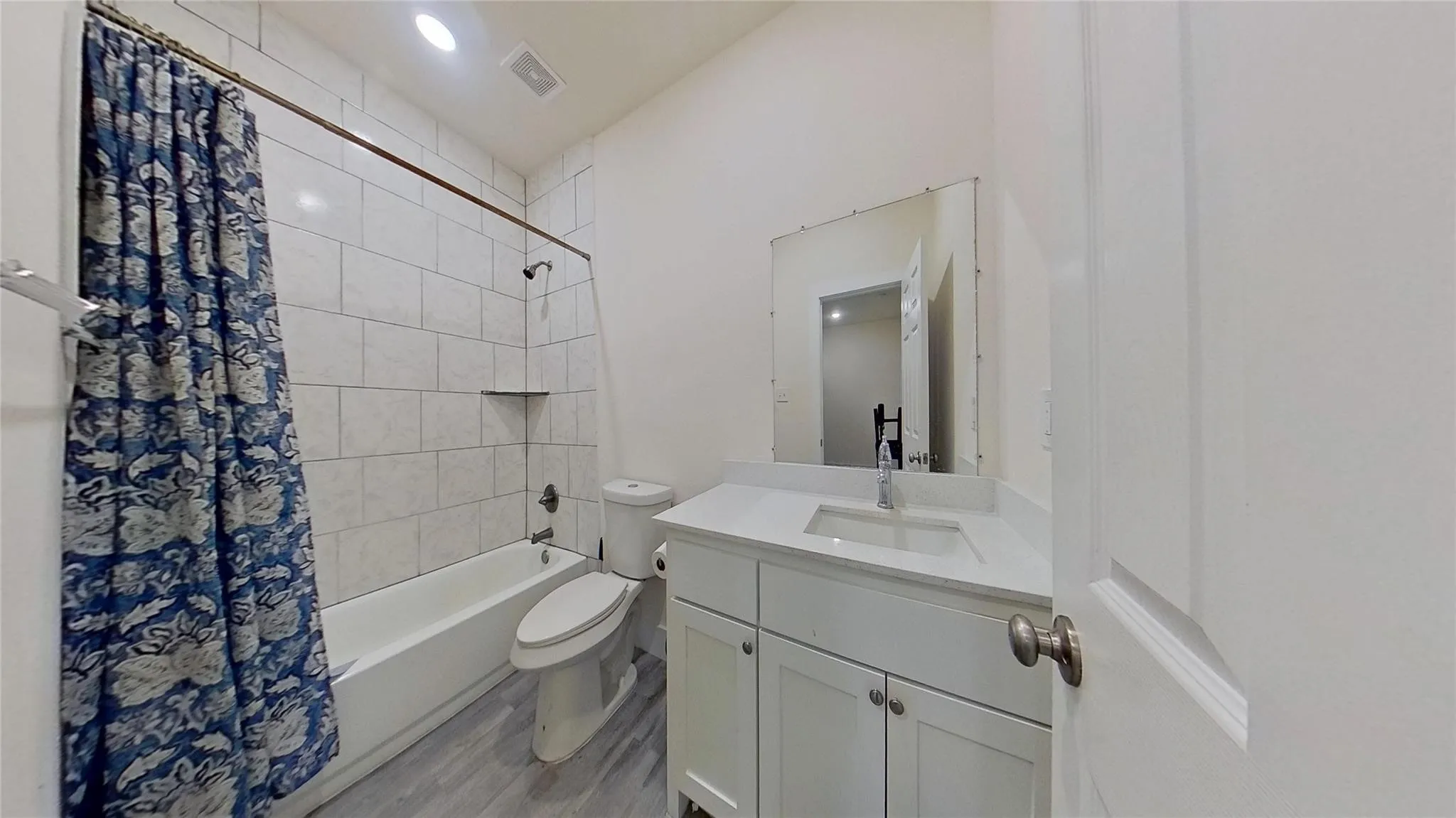 White vanity with a single sink, light-toned countertop, and chrome faucet
