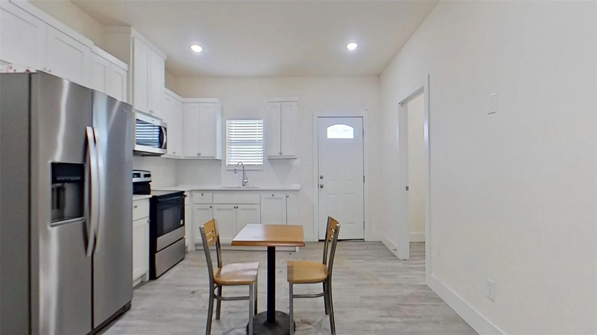 Kitchen featuring white cabinetry, stainless steel appliances, and wood-finish flooring