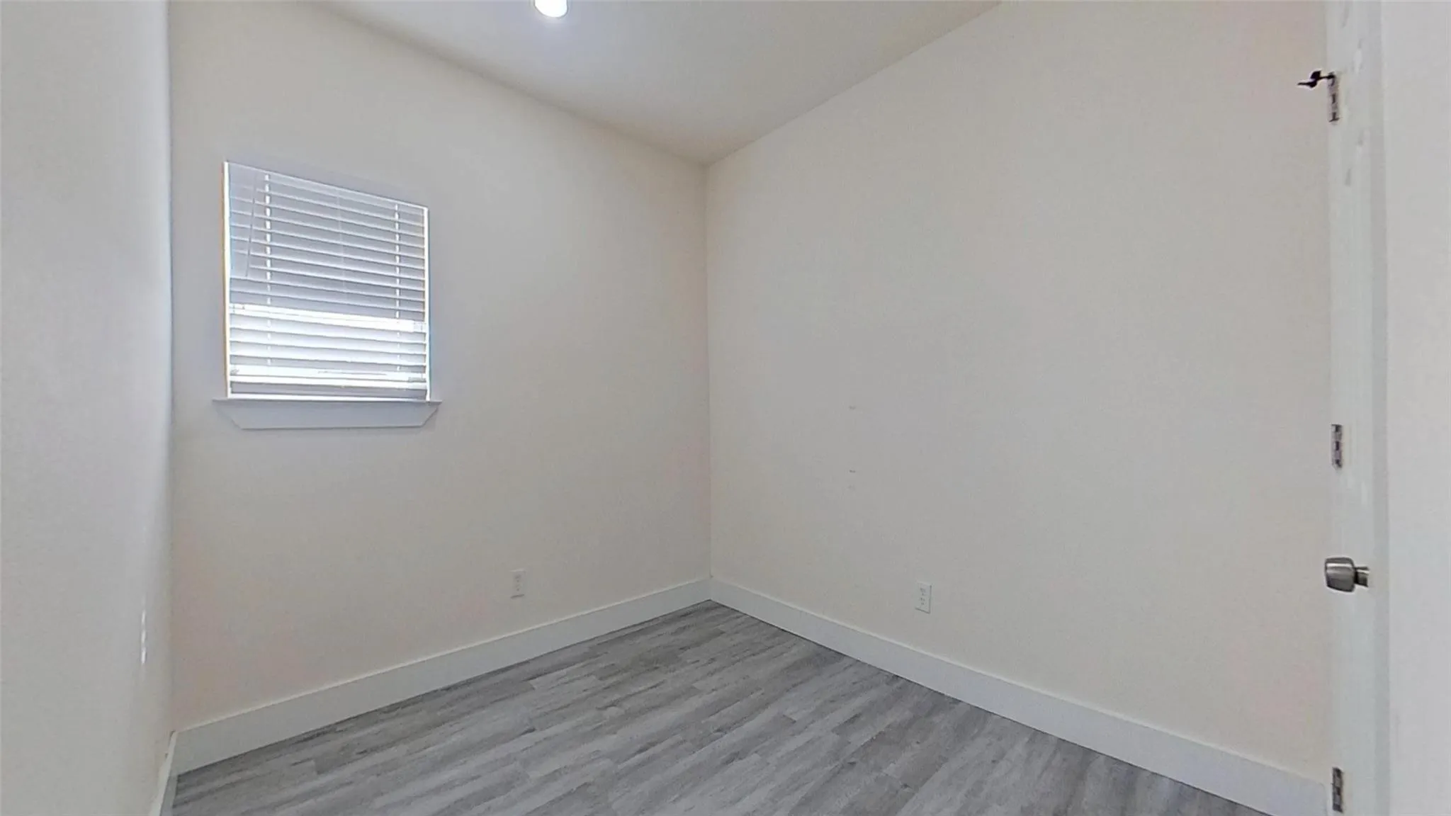 Wood-finish flooring, neutral wall tones, and a window with blinds