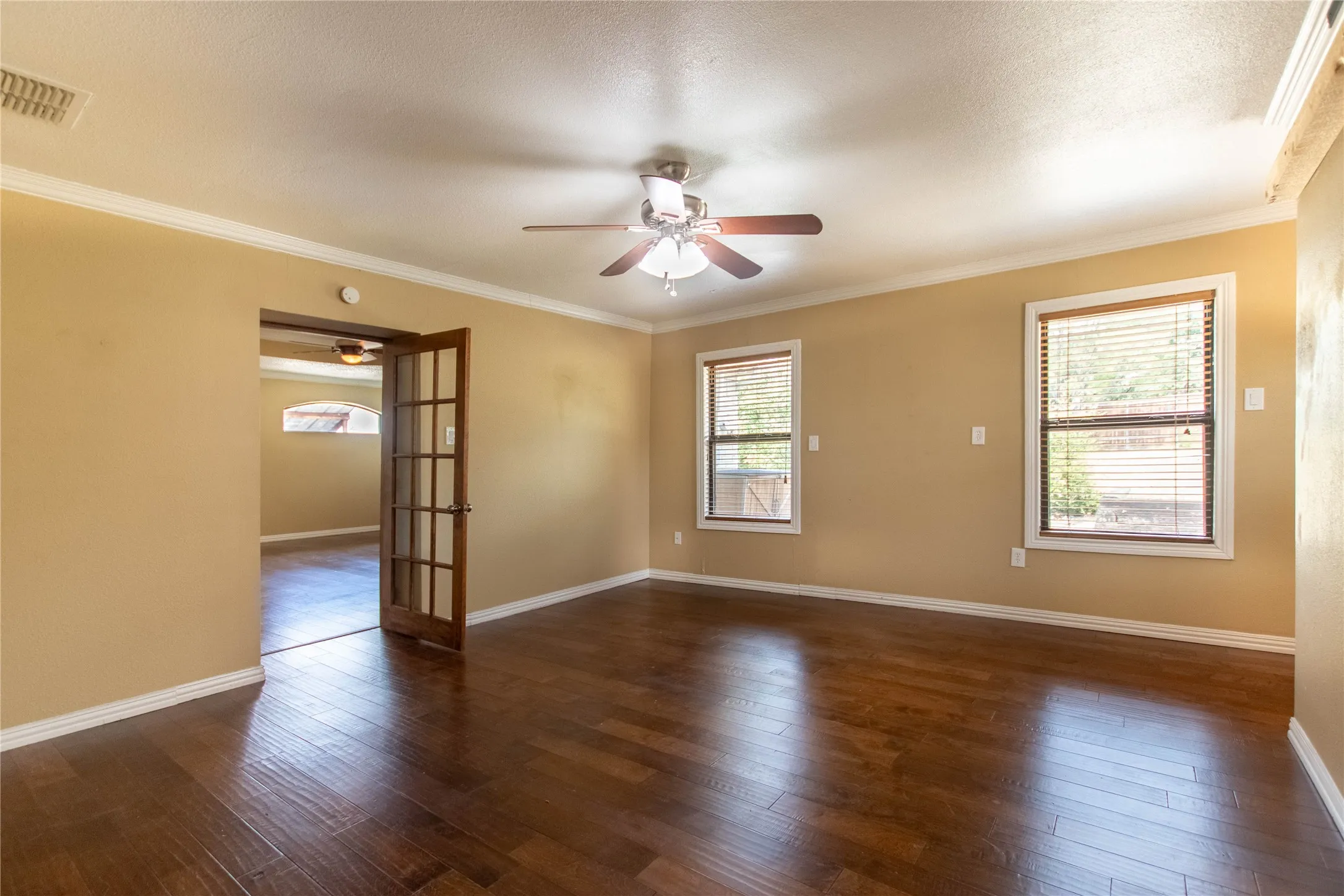 Hardwood-style flooring throughout, crown molding, and a ceiling fan with integrated lighting