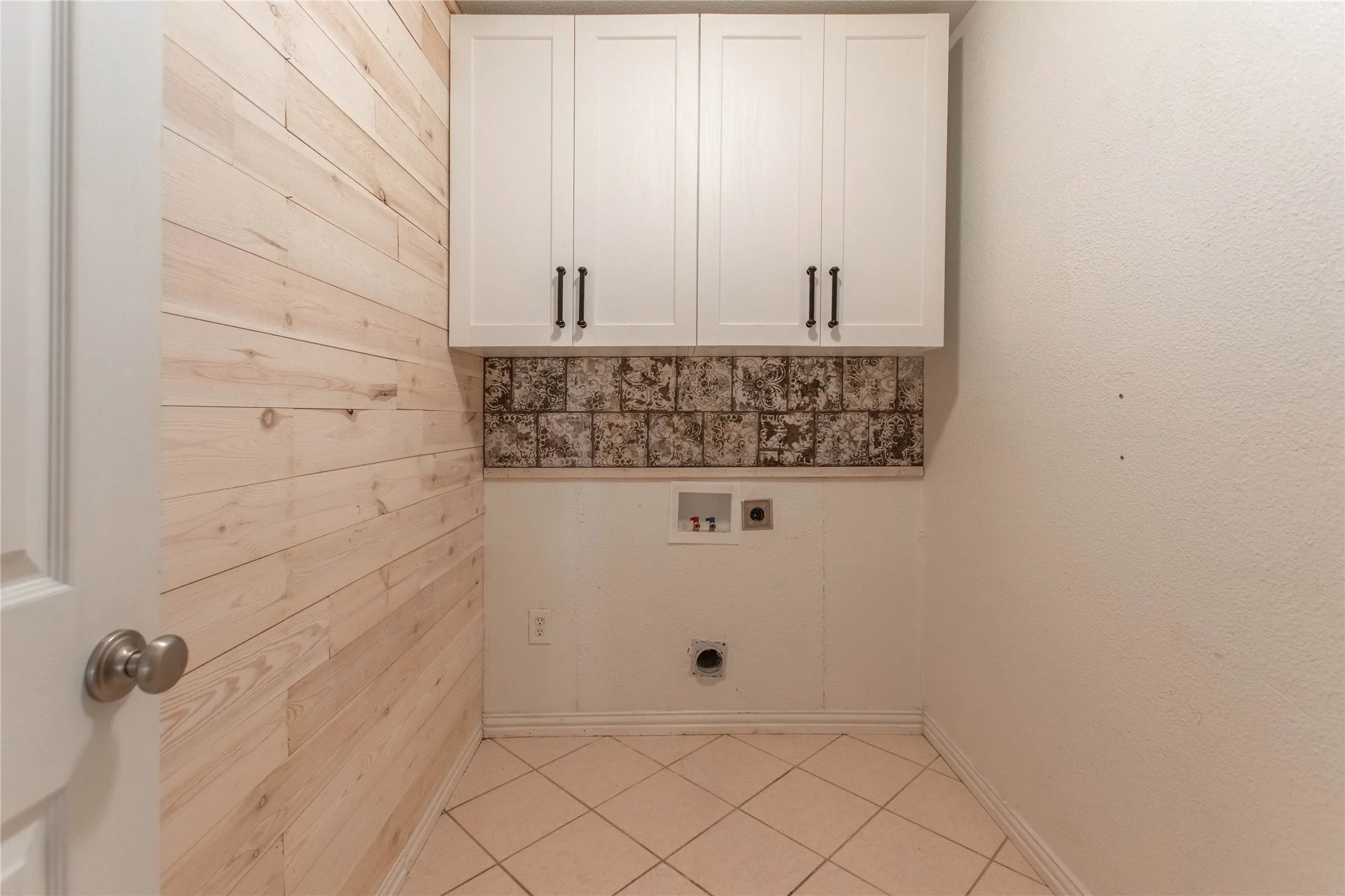 Light wood-paneled accent wall with upper white cabinetry and dark hardware