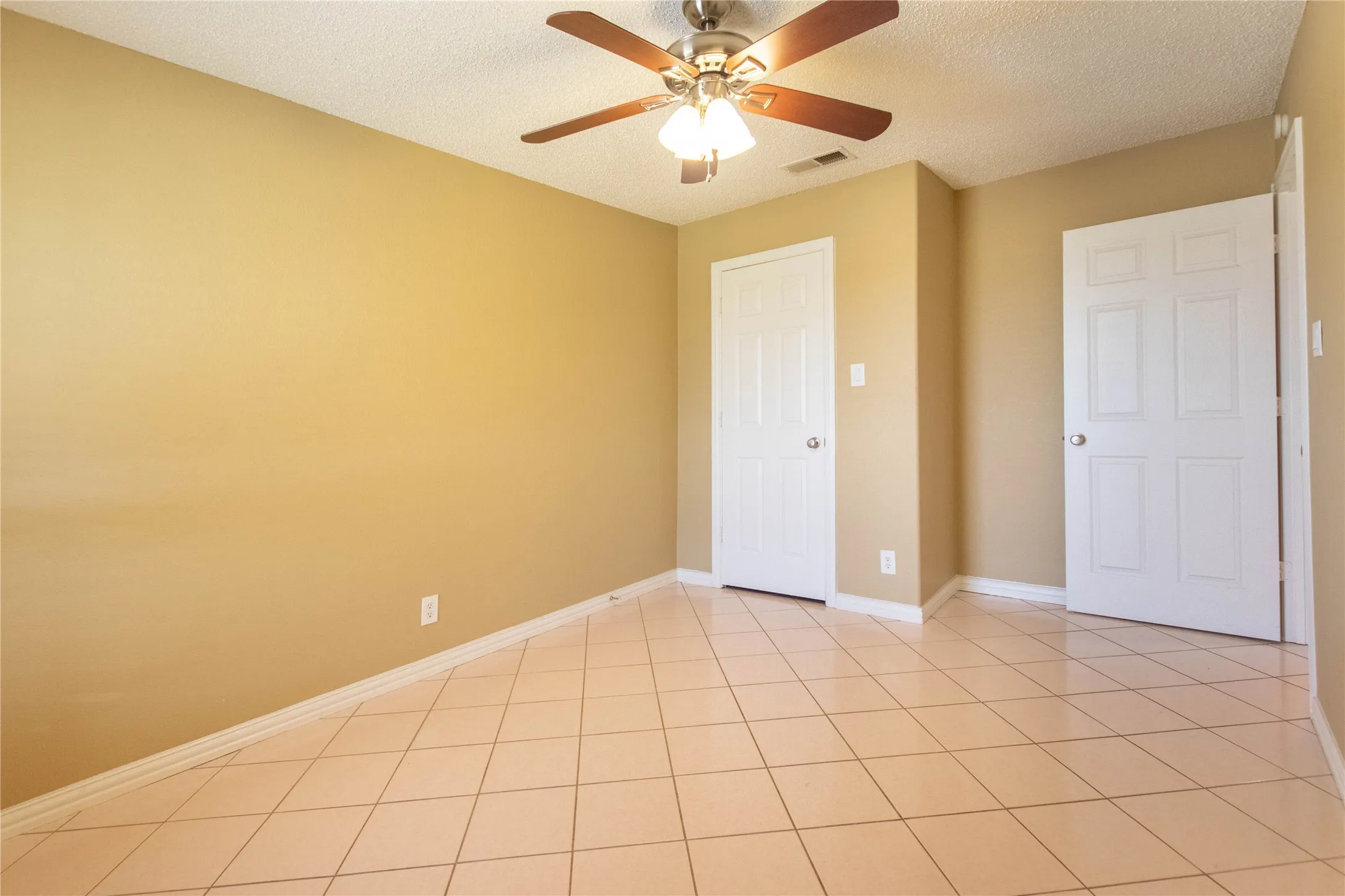 Tiled flooring, ceiling fan with light fixture, and two panel doors