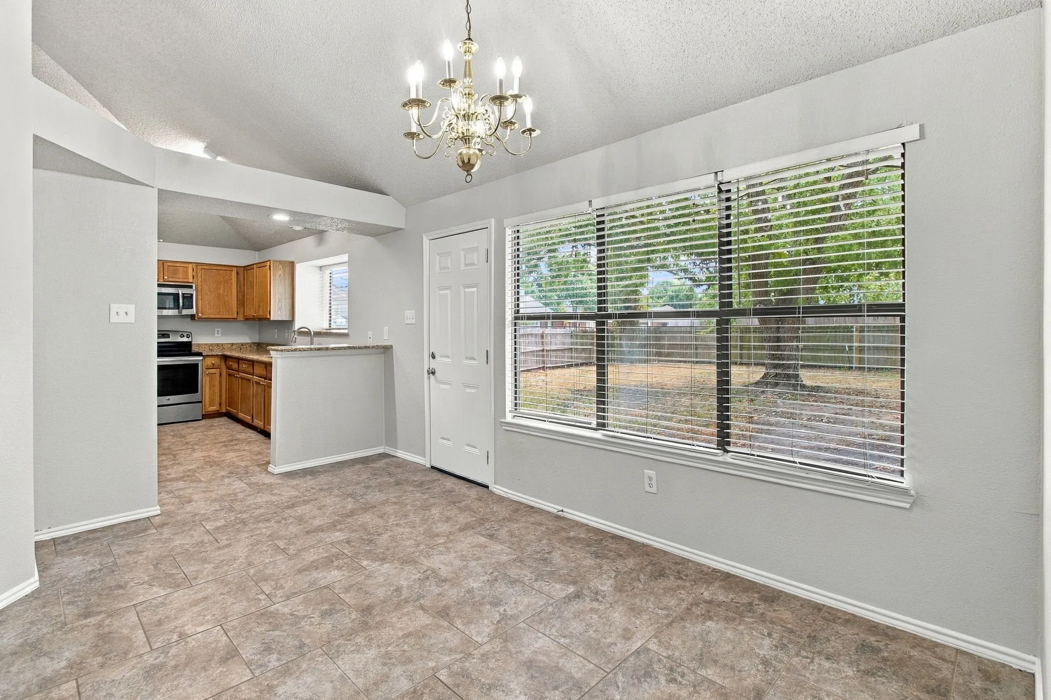 Kitchen and dining area featuring vaulted ceilings, tile flooring, and a chandelier