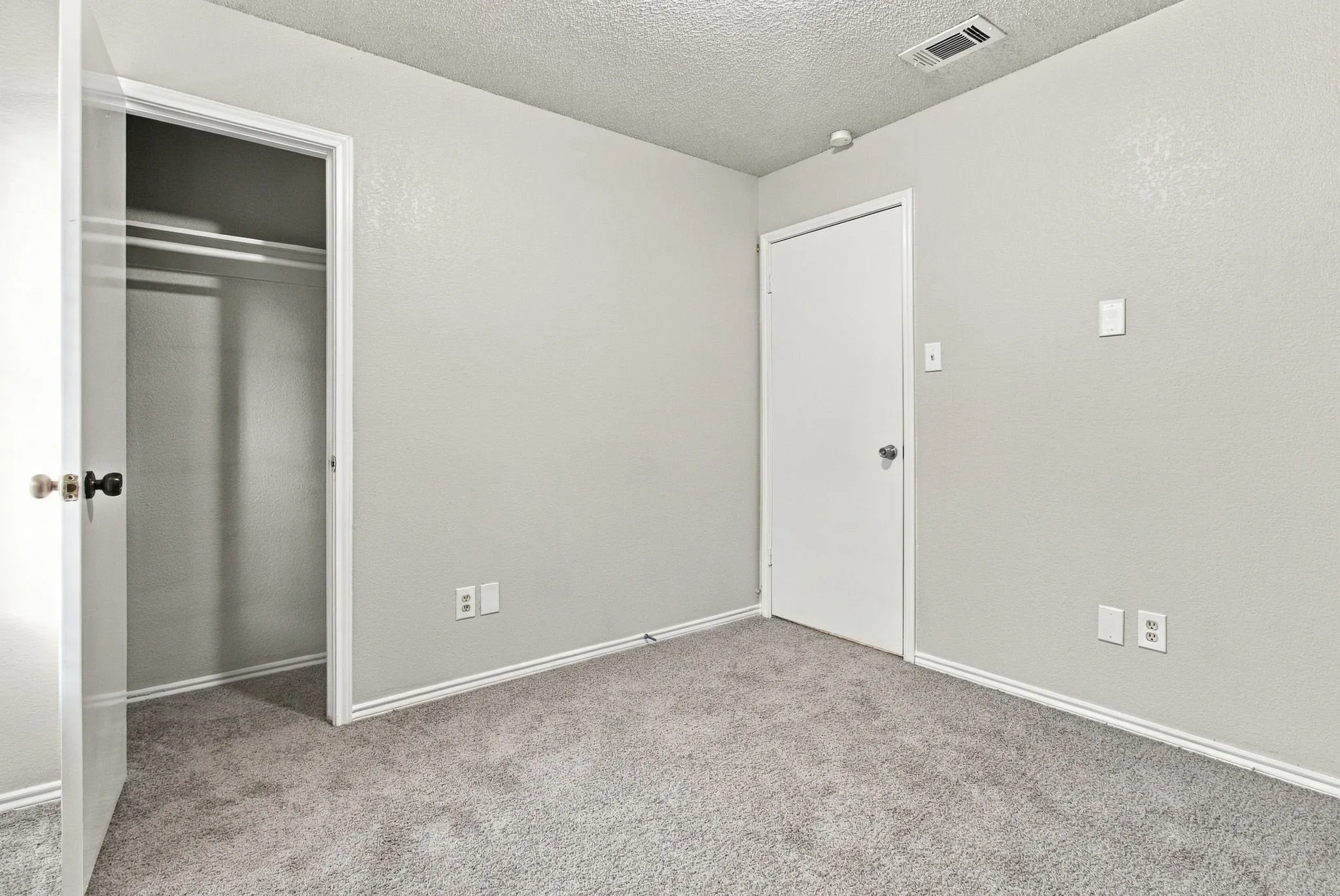 Plush gray carpeting, white trim, and a built-in closet with hanging rods