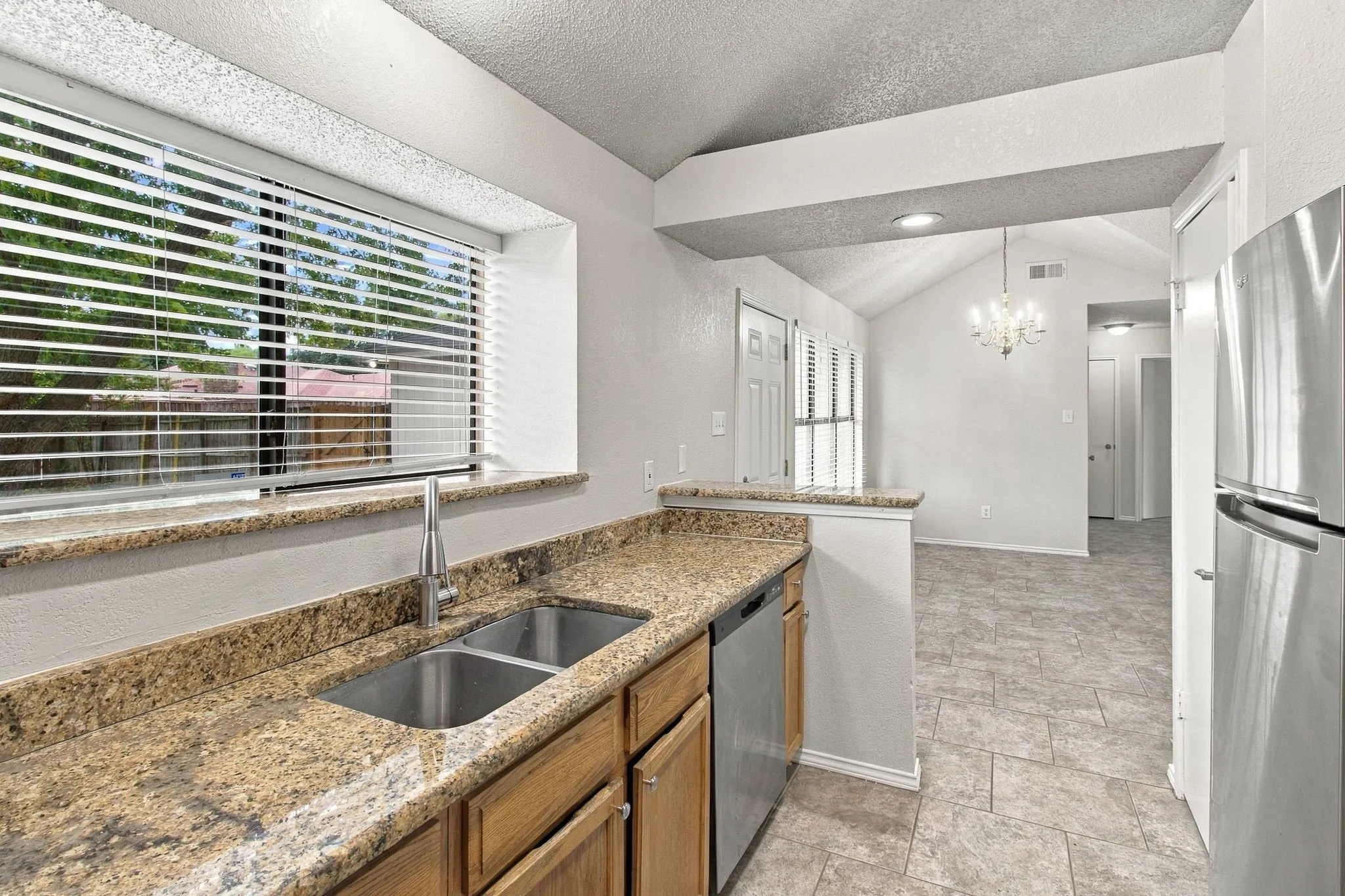 Kitchen featuring granite countertops, stainless steel sink, and wood cabinetry