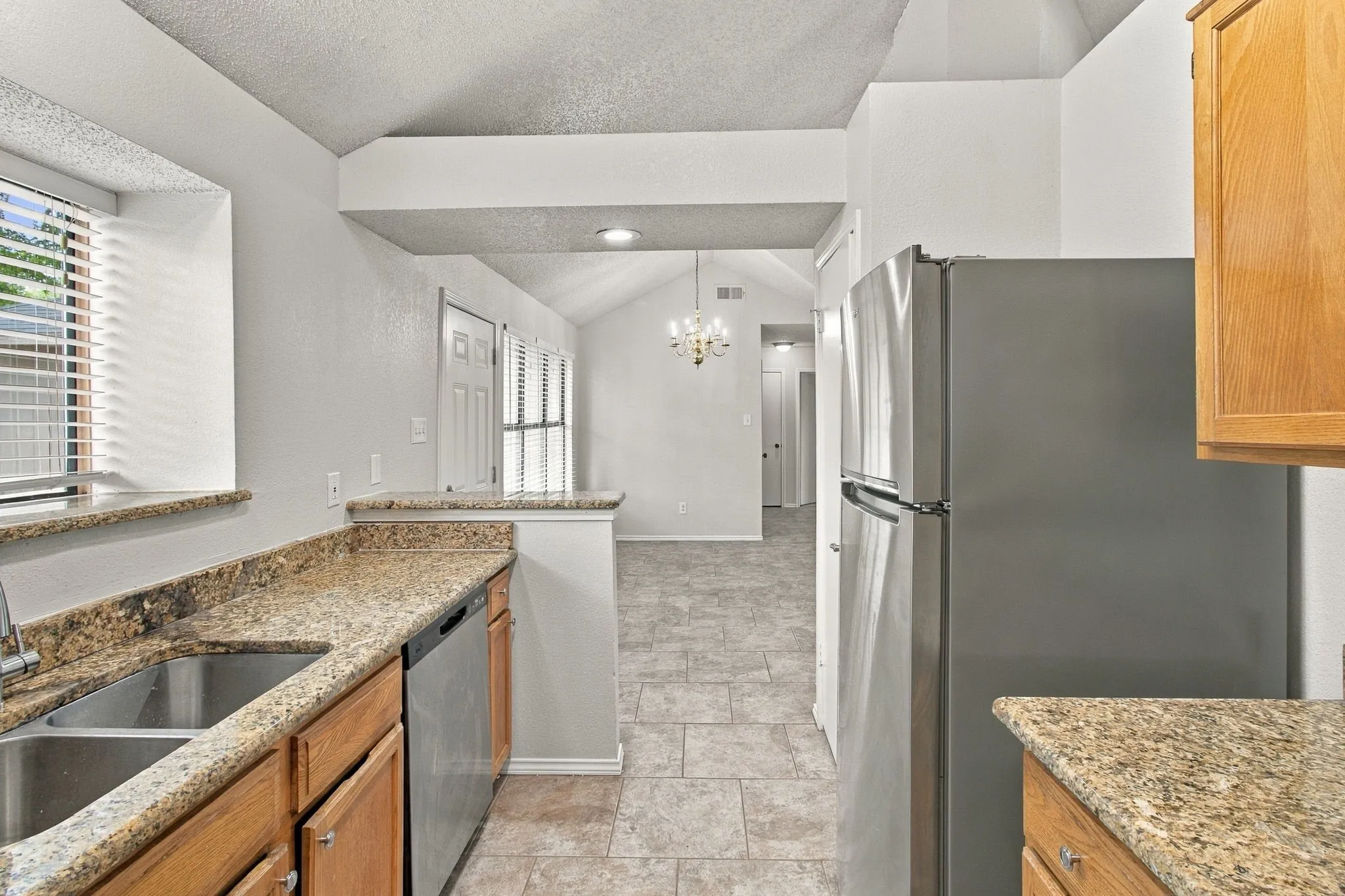 Kitchen featuring light wood cabinetry, granite-style countertops, and a double basin stainless steel sink