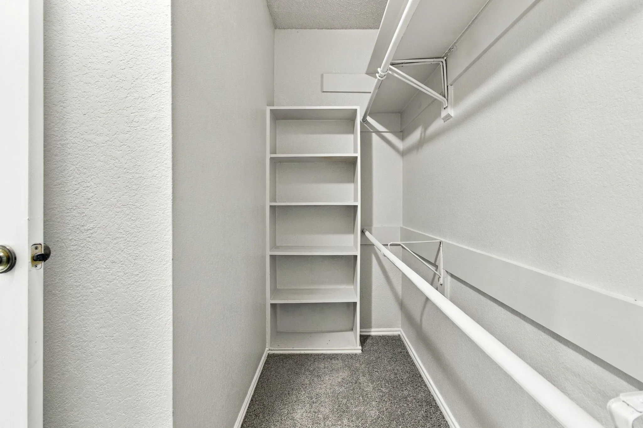 Built-in shelving, white walls, and gray carpet