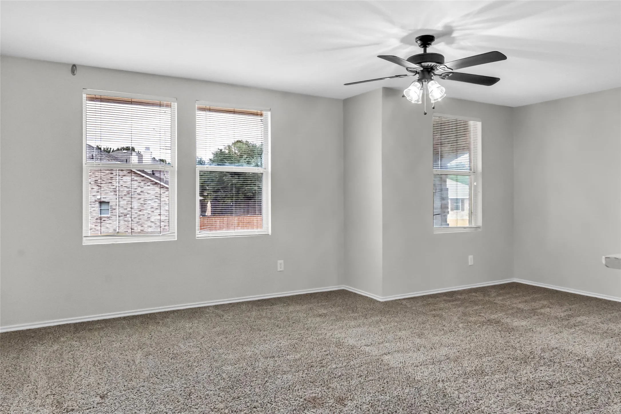 Carpeted flooring, multiple windows, ceiling fan with integrated lighting, and neutral wall tones