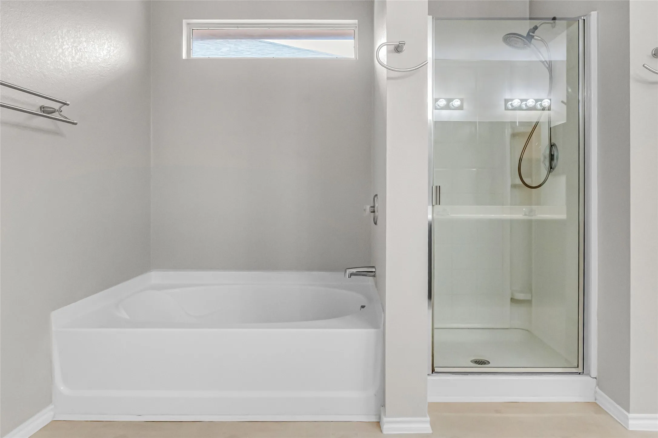 Built-in bathtub, glass-enclosed shower, shower with built-in shelving, chrome fixtures, and a transom window