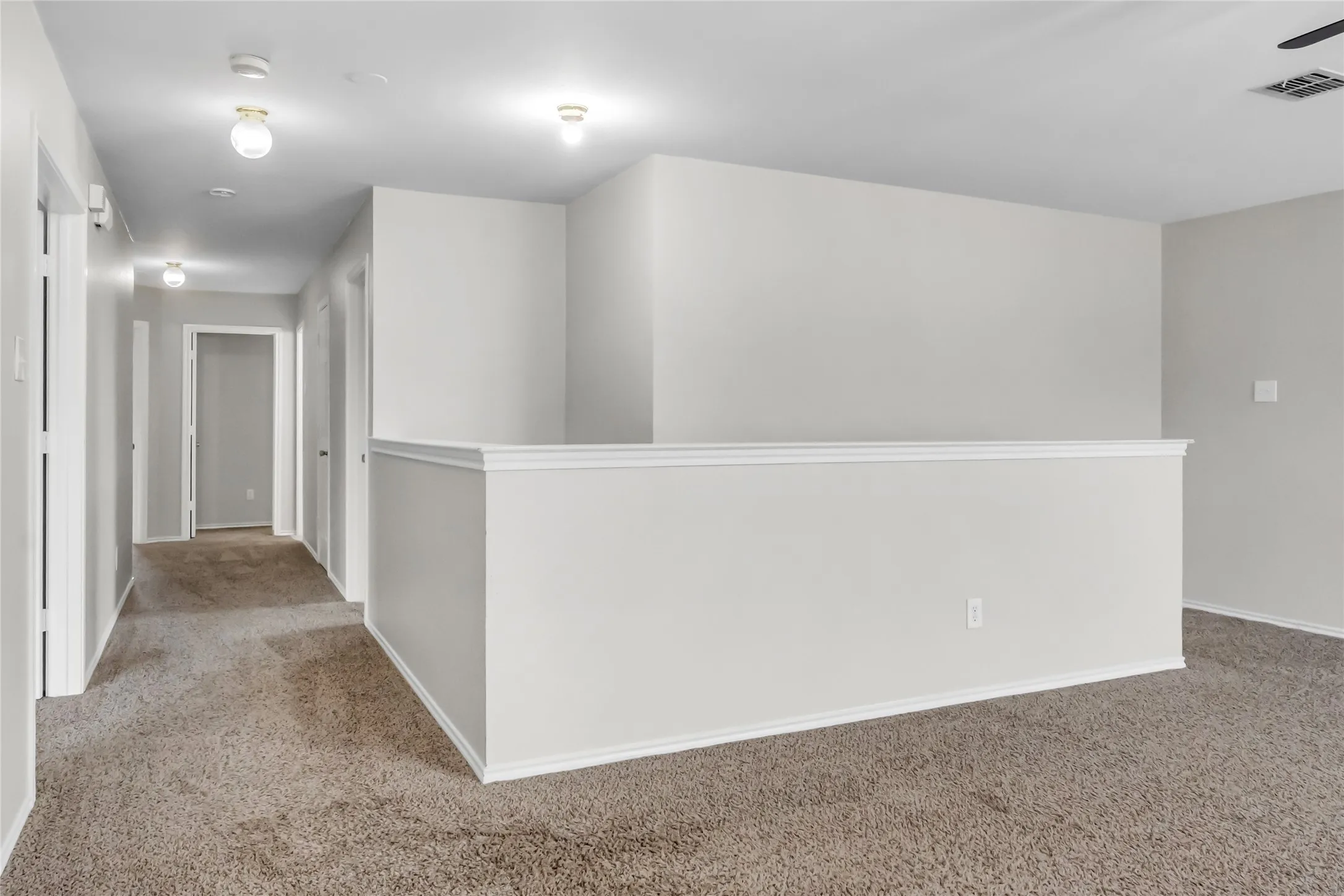 Open concept loft area featuring neutral-toned carpet, light gray wall paint, and white trim