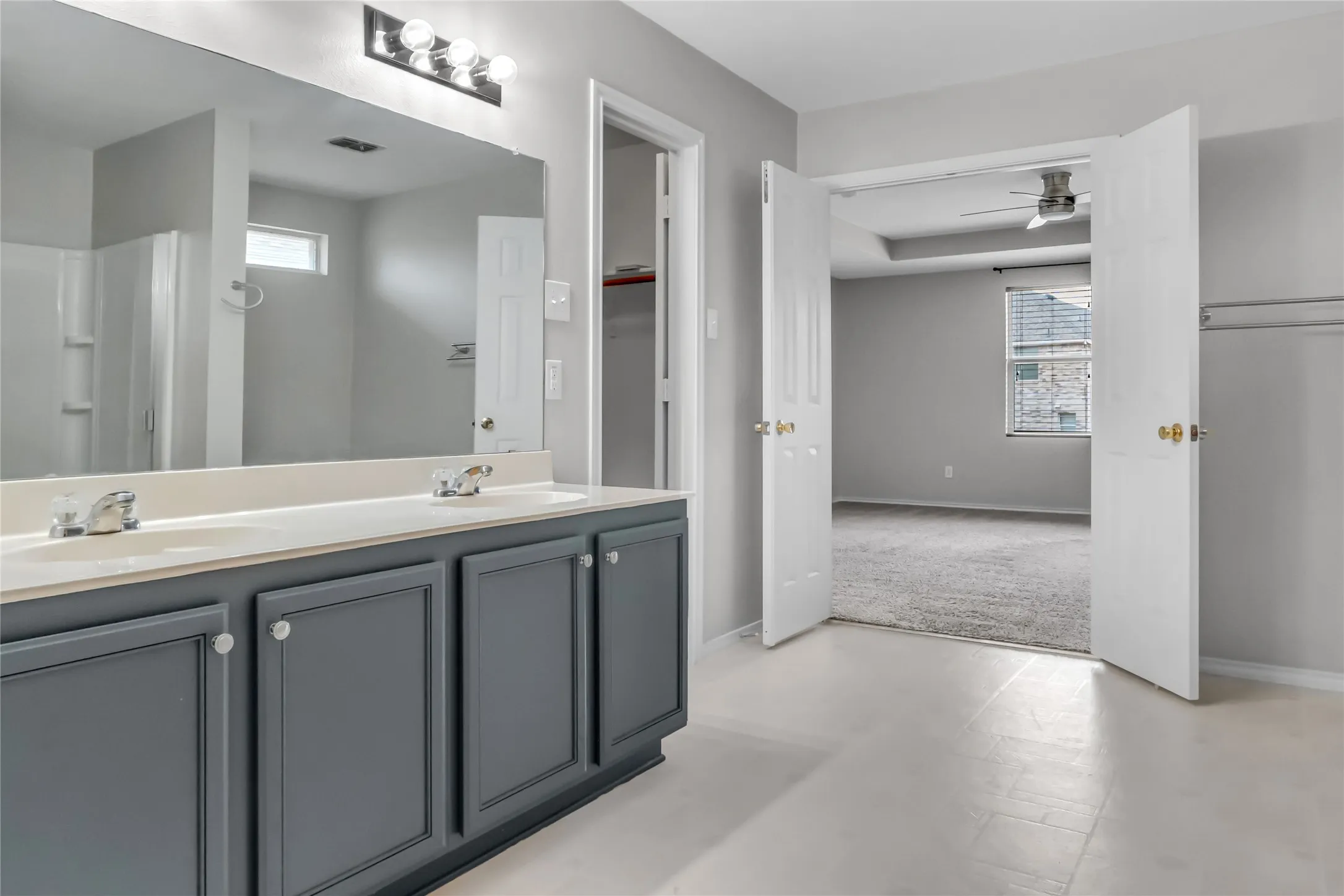 Double vanity with white countertop and integrated sinks, brushed nickel faucets, and dark gray cabinetry