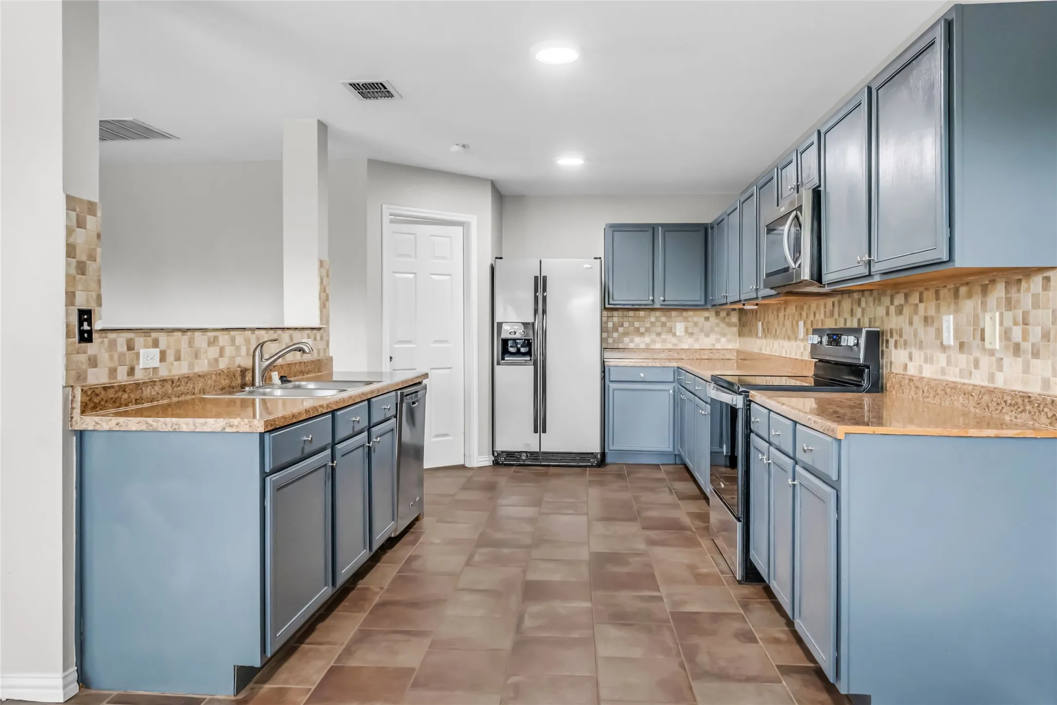Kitchen featuring wood-finish flooring, blue cabinetry, granite-style countertops, and a tile backsplash