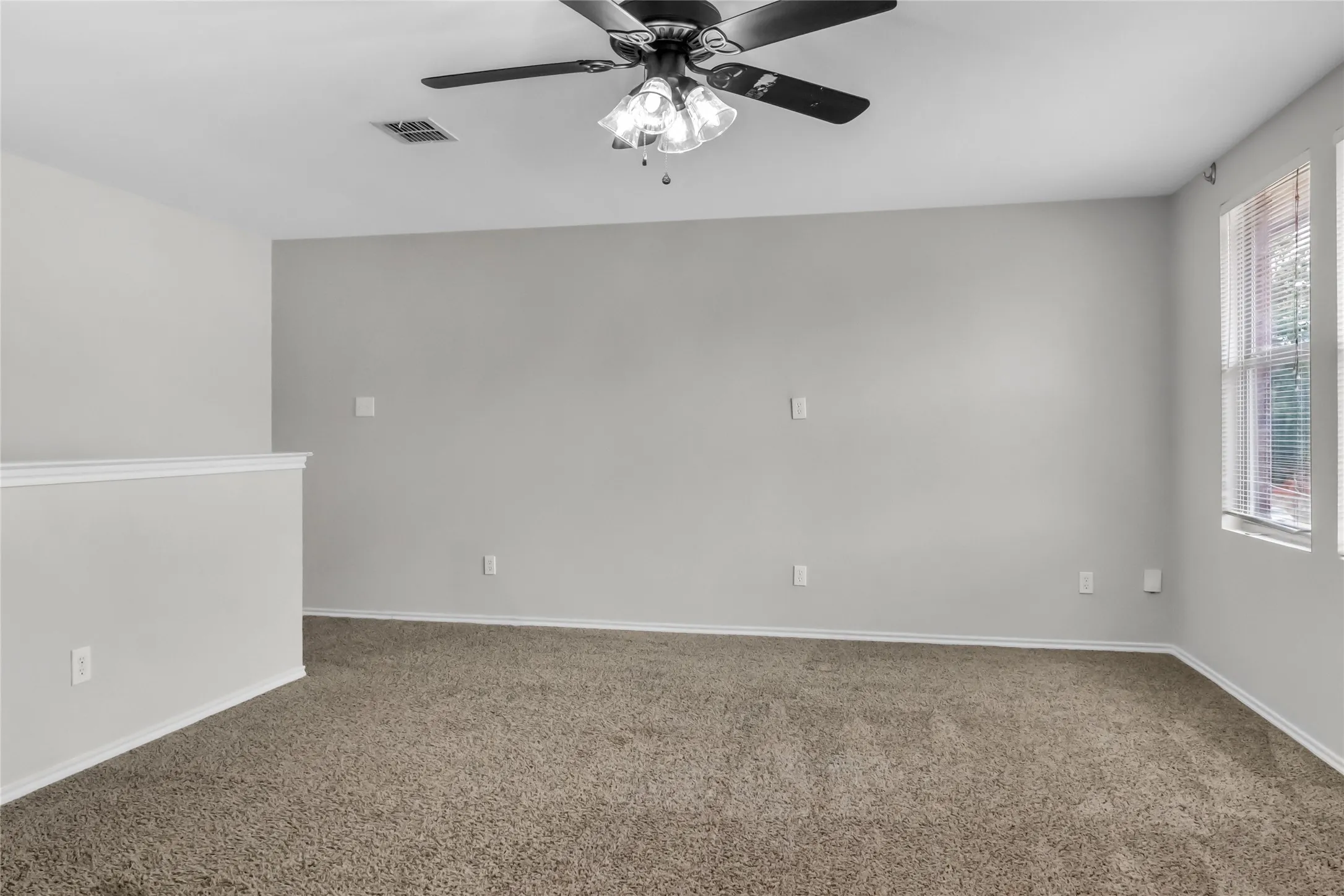 Carpeted flooring, light grey wall paint, ceiling fan with light fixture, and windows with blinds