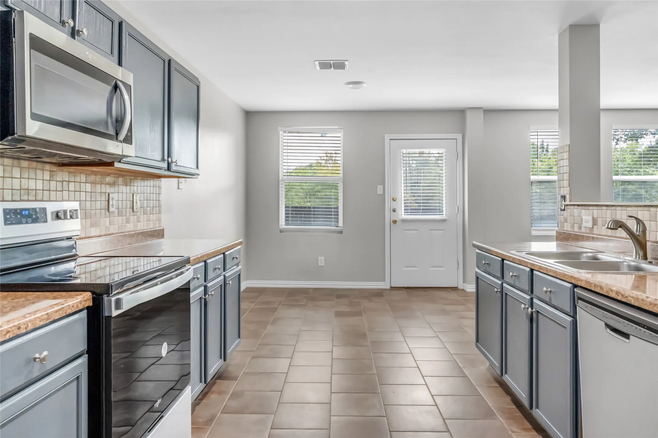 Kitchen featuring tile flooring, dark cabinetry, and stone-finish countertops