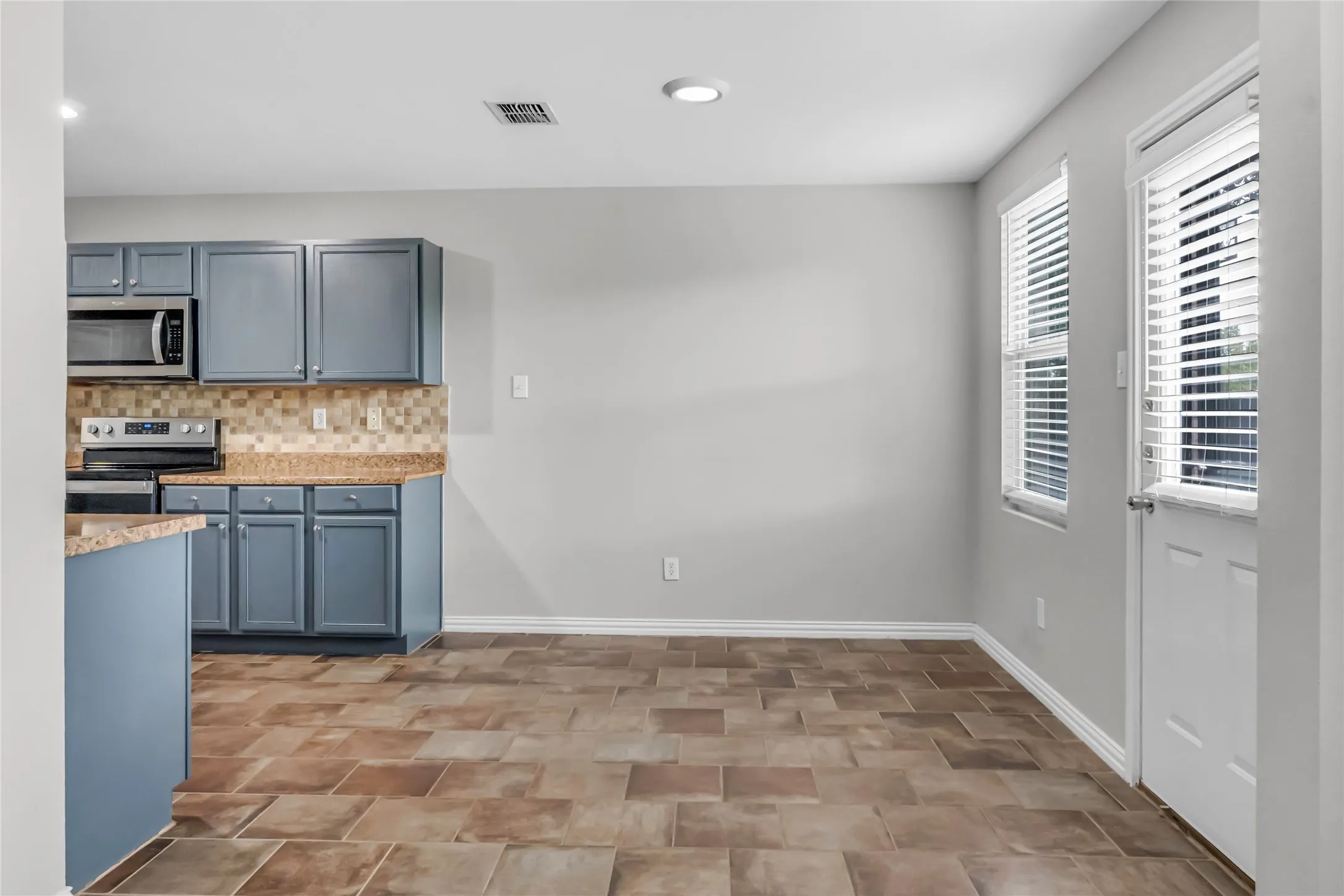 Kitchen with blue cabinetry, stainless steel appliances, and a tiled backsplash