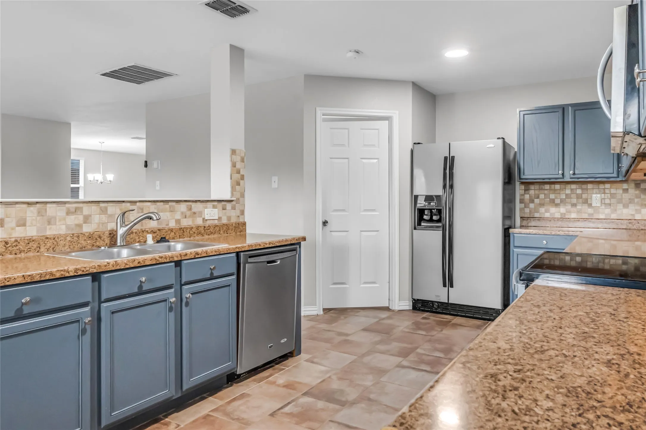 Kitchen featuring wood-finish flooring, blue cabinetry, a stainless steel refrigerator, and a double basin sink