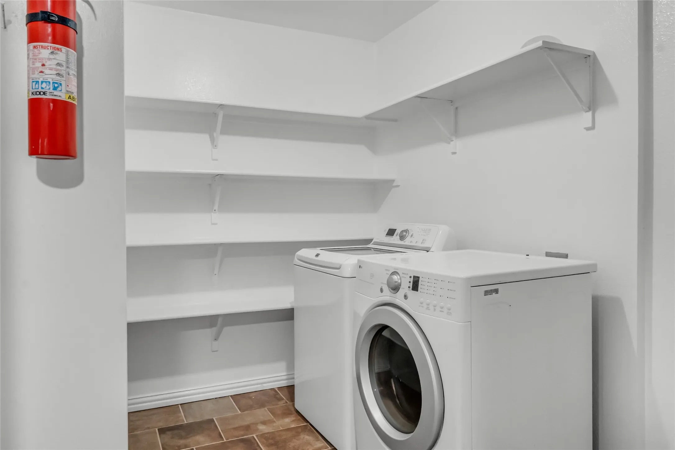Integrated laundry area with tile flooring and extensive wall-mounted shelving