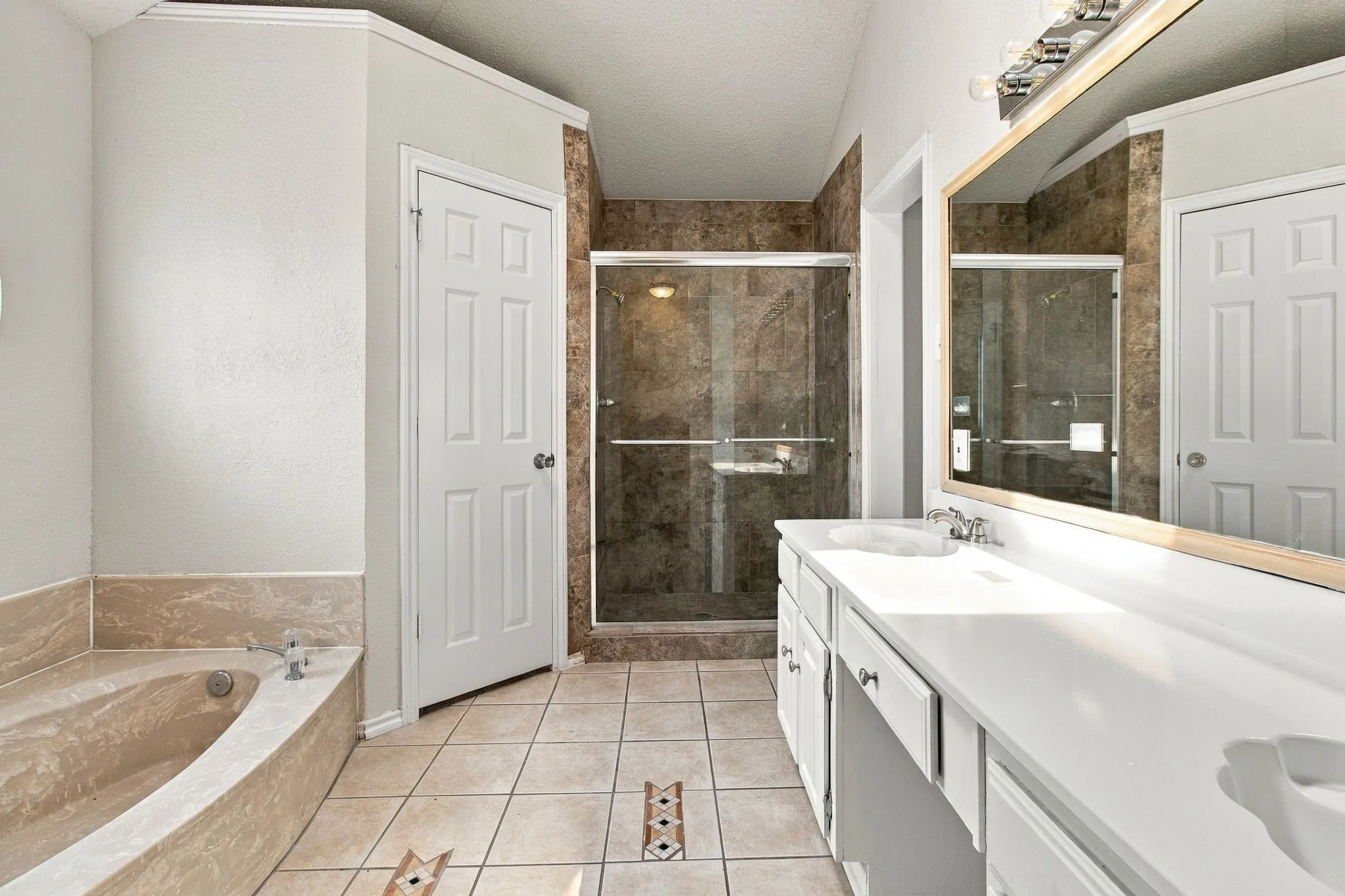 Dual sink vanity with white countertop, built-in soaking tub, glass-enclosed shower, and tile flooring