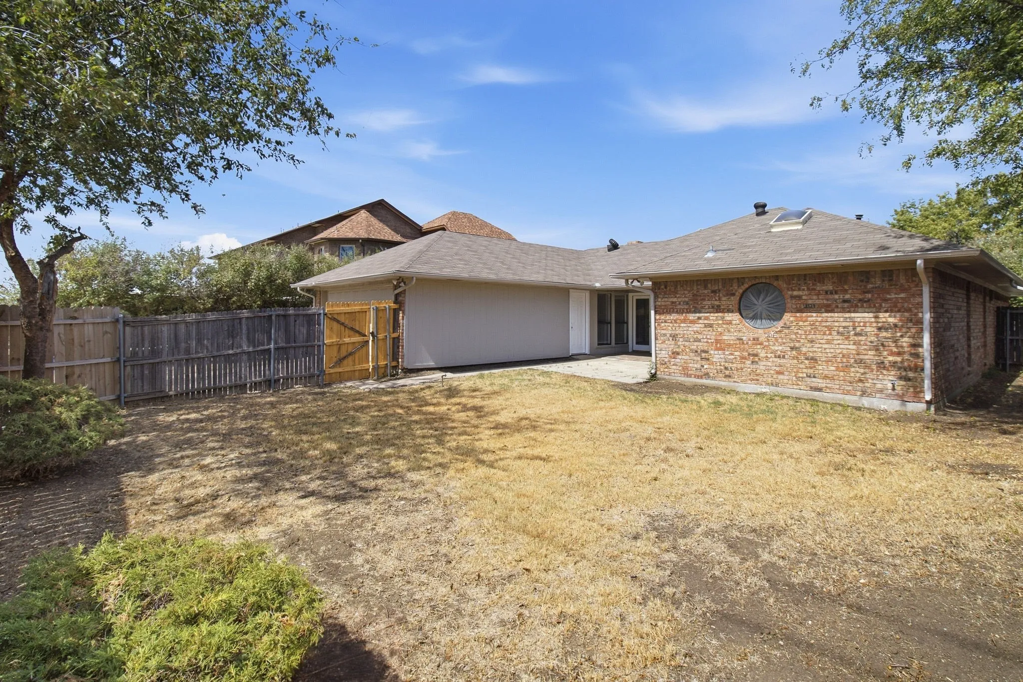 Brick exterior with a skylight, circular window, and a wood privacy fence