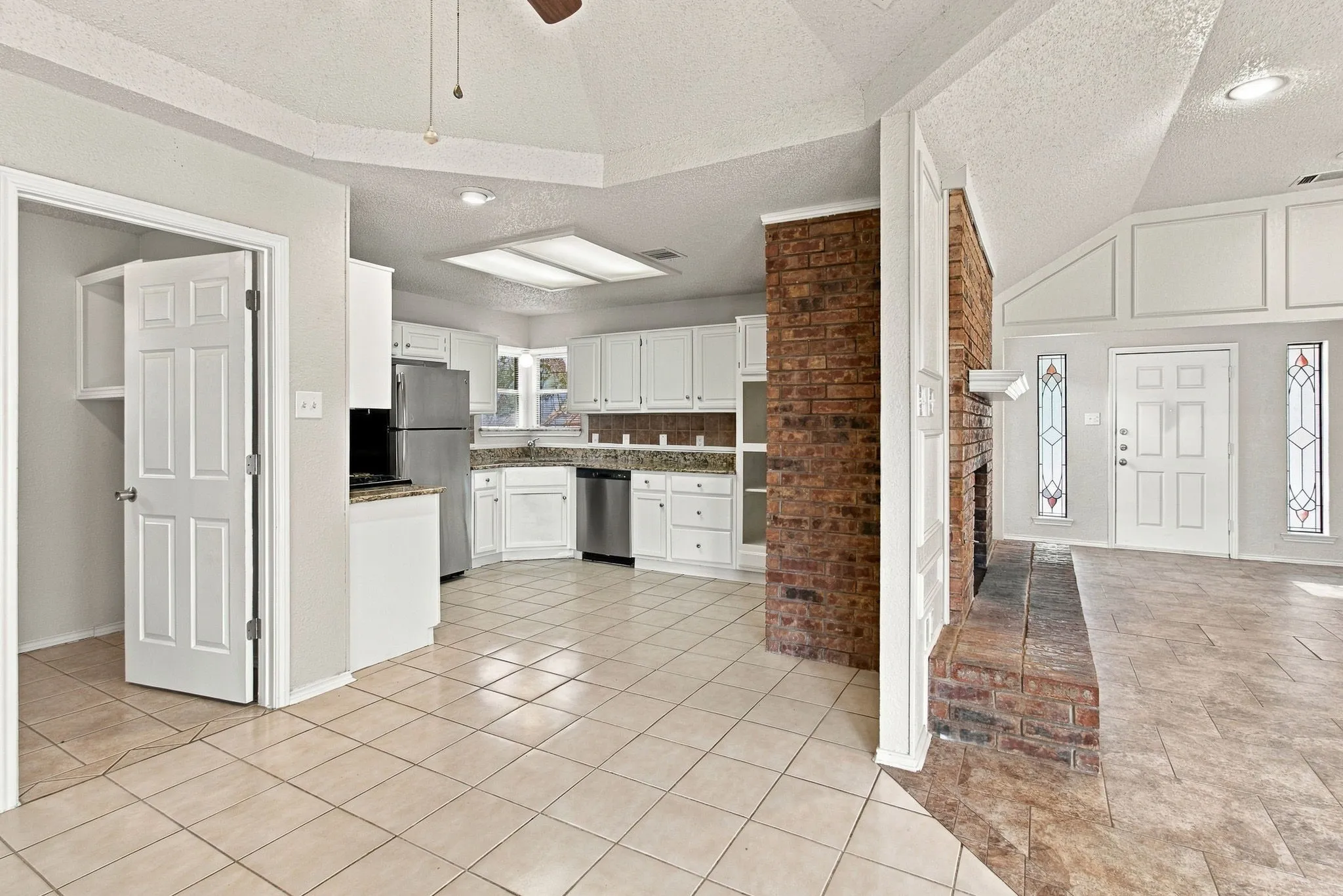 Kitchen featuring white cabinetry, granite-style countertops, stainless steel appliances, and tile flooring