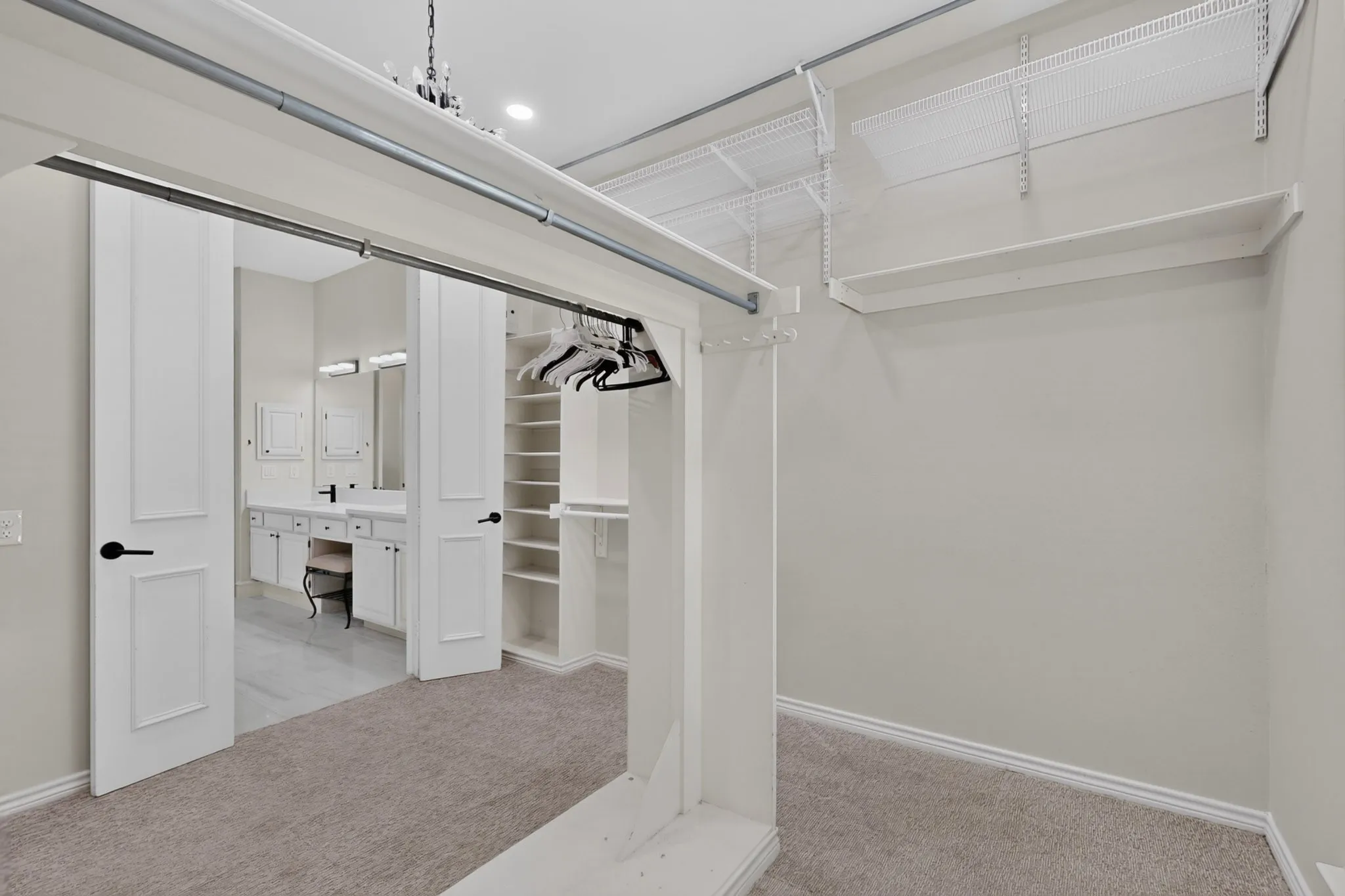 Carpeted walk-in closet with built-in shelving, wire shelving, and hanging rods