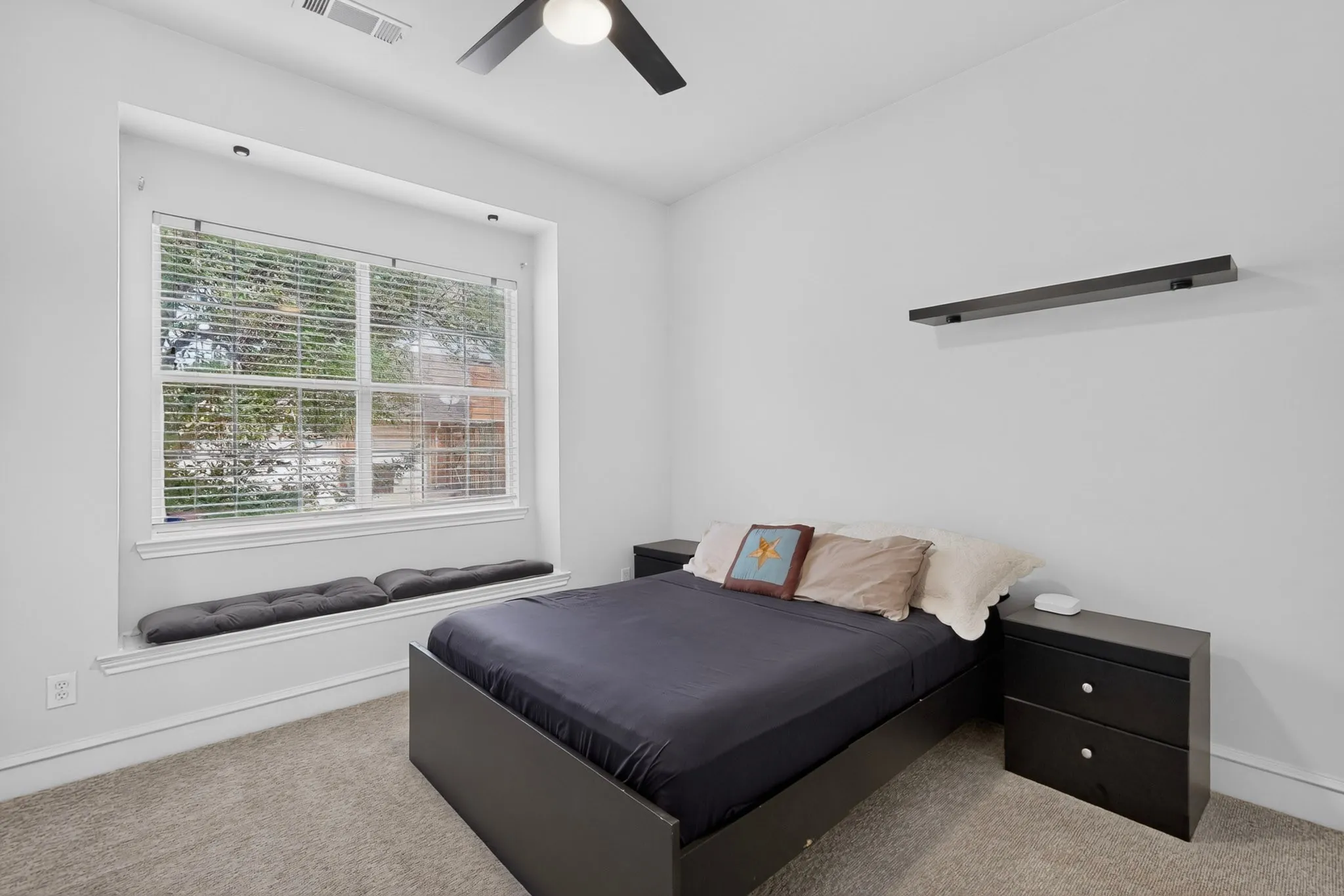 Recessed window with built-in seating, modern ceiling fan, and wall-mounted shelving