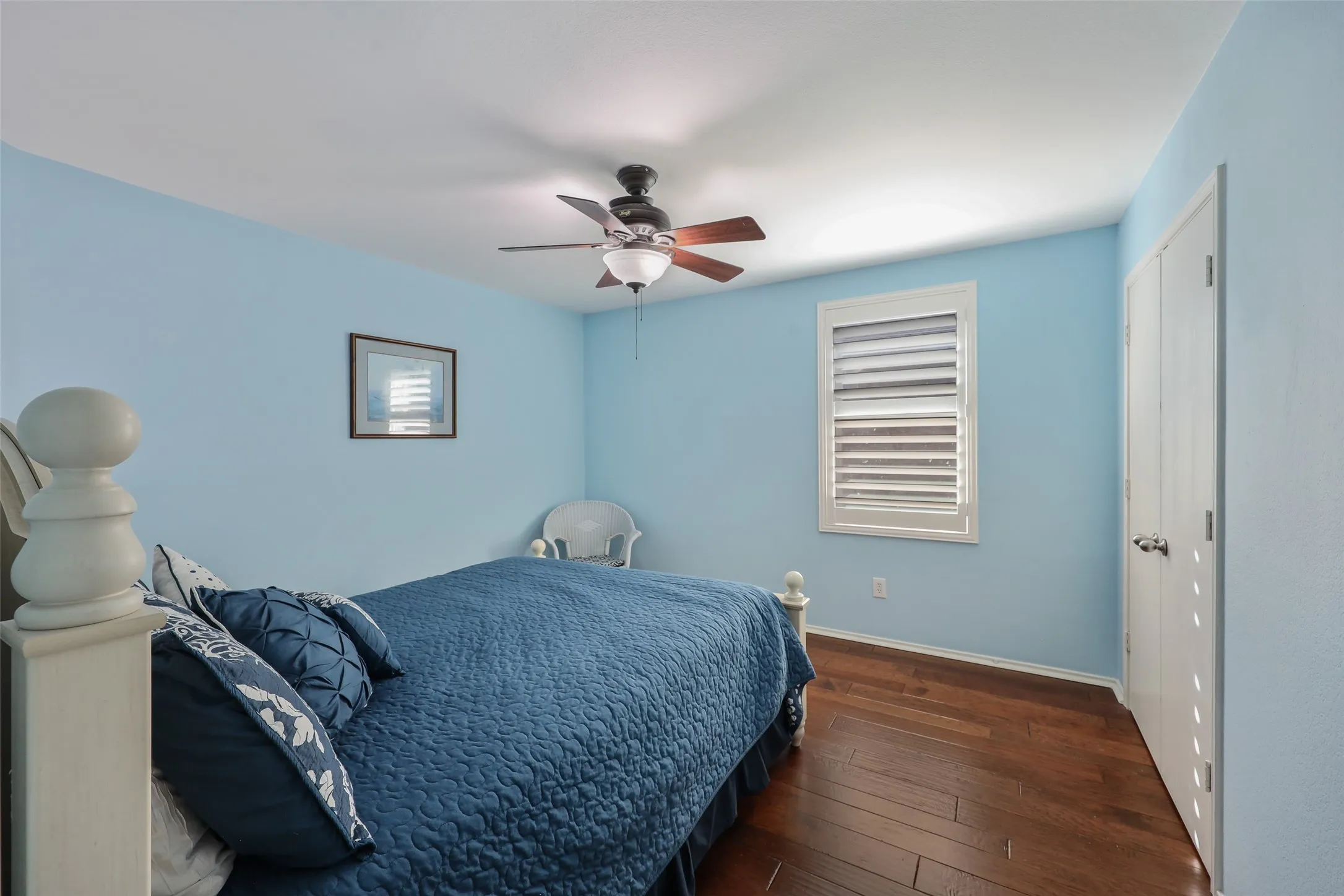 Wood-finish flooring, ceiling fan with integrated lighting, window with plantation shutters, and bi-fold closet doors
