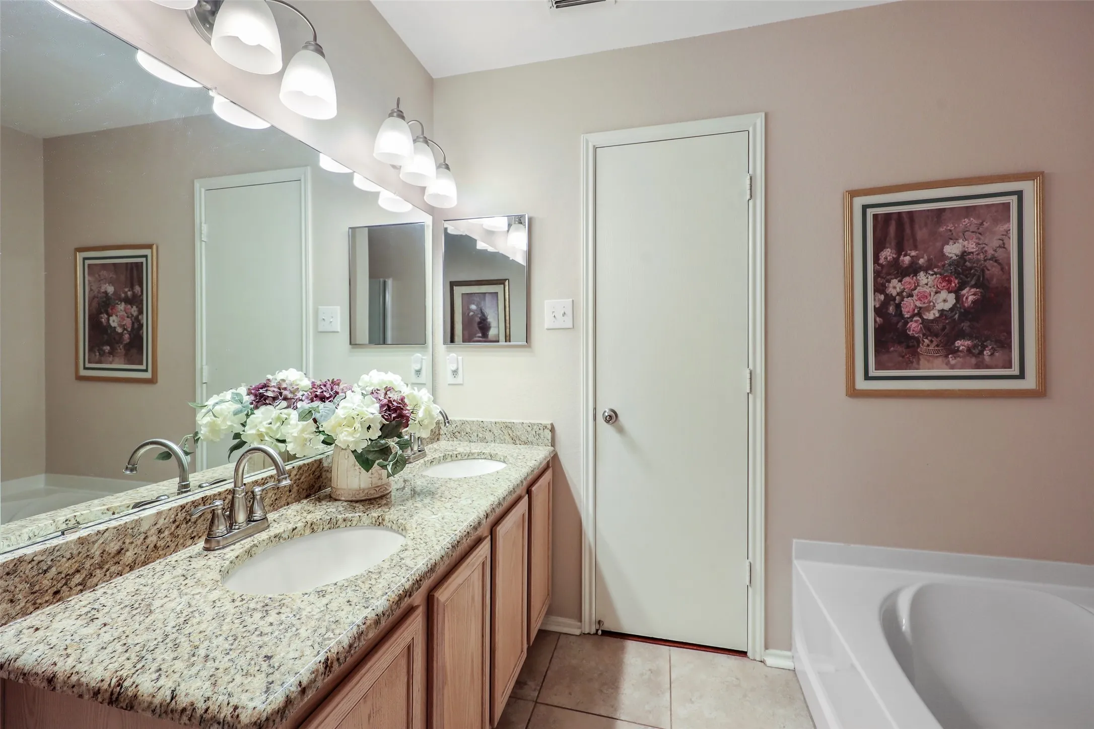 Spa-inspired primary bathroom featuring dual vanity with granite countertop, polished nickel fixtures, and ample storage