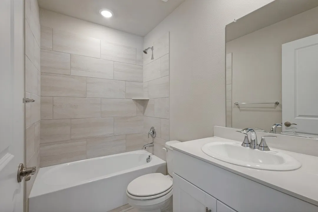 Full bathroom featuring a white vanity with an undermount sink, chrome fixtures, a large frameless mirror, and a tiled shower-tub combination