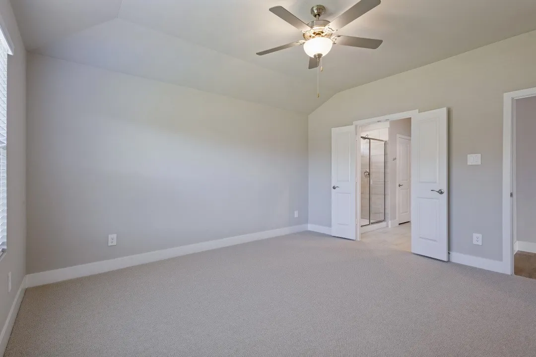 Vaulted ceiling with a ceiling fan, light-toned carpeting, and white baseboards