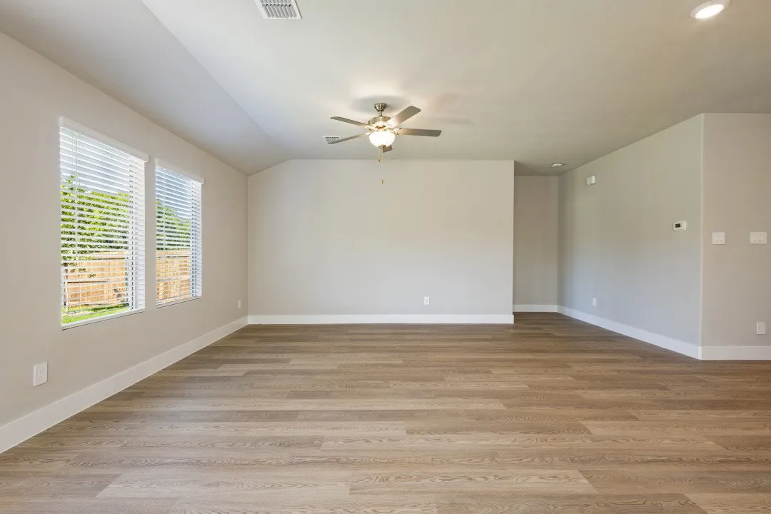 Spacious room featuring wood-finish flooring, multiple windows with blinds, a ceiling fan, and recessed lighting