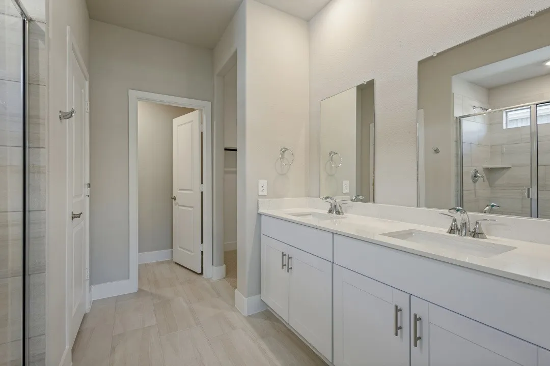 Dual vanity with undermount sinks, chrome fixtures, and white cabinetry