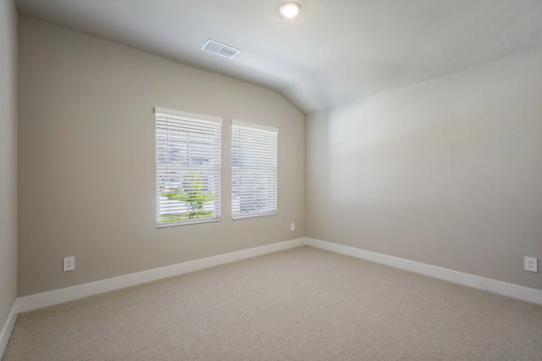 Vaulted ceiling, recessed lighting, dual windows with blinds, light-colored carpeting, and neutral wall tones