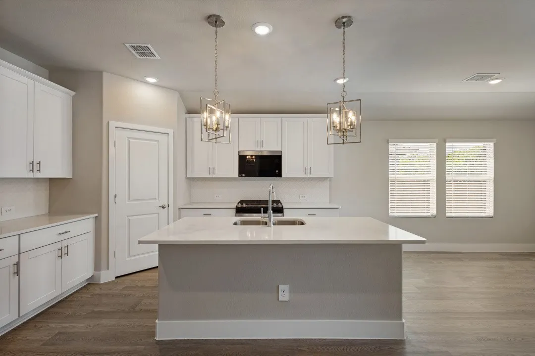 Kitchen featuring a center island, white cabinetry, integrated sink, pendant lighting, and wood-finish flooring