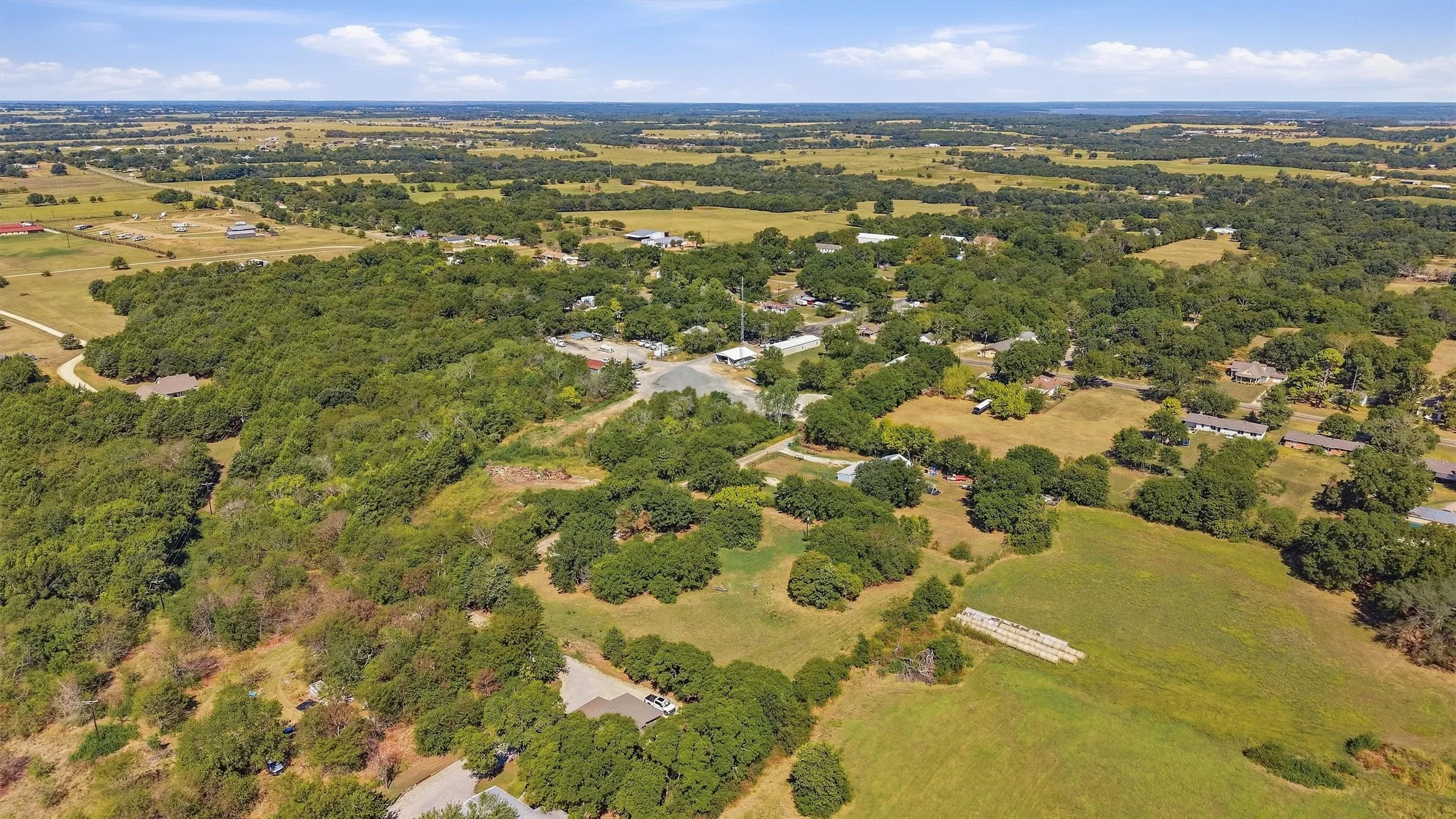 Expansive acreage featuring abundant mature trees, open pastures, and distant residential structures