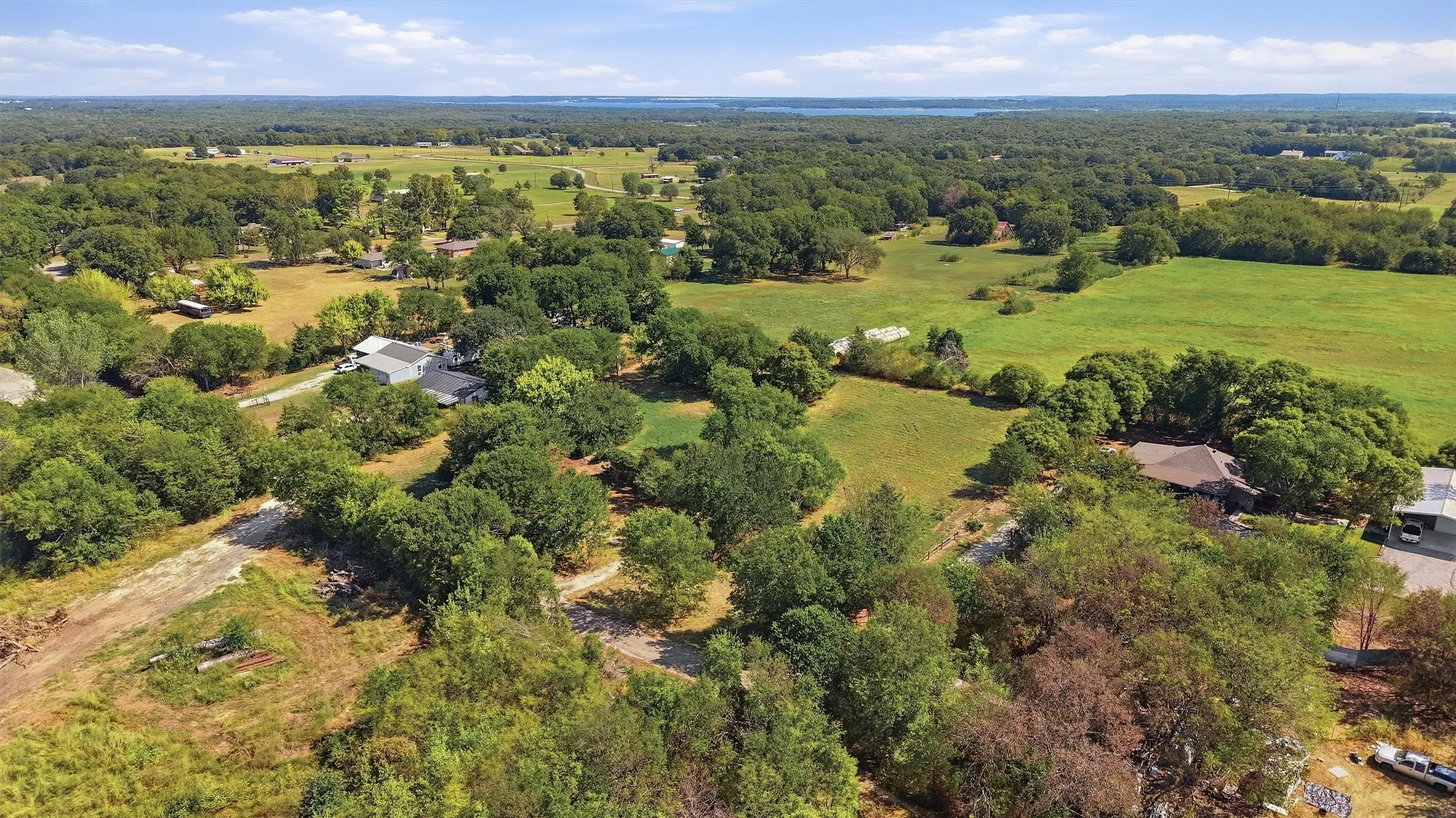 Expansive rural landscape featuring scattered residences, mature trees, and open fields under a clear sky