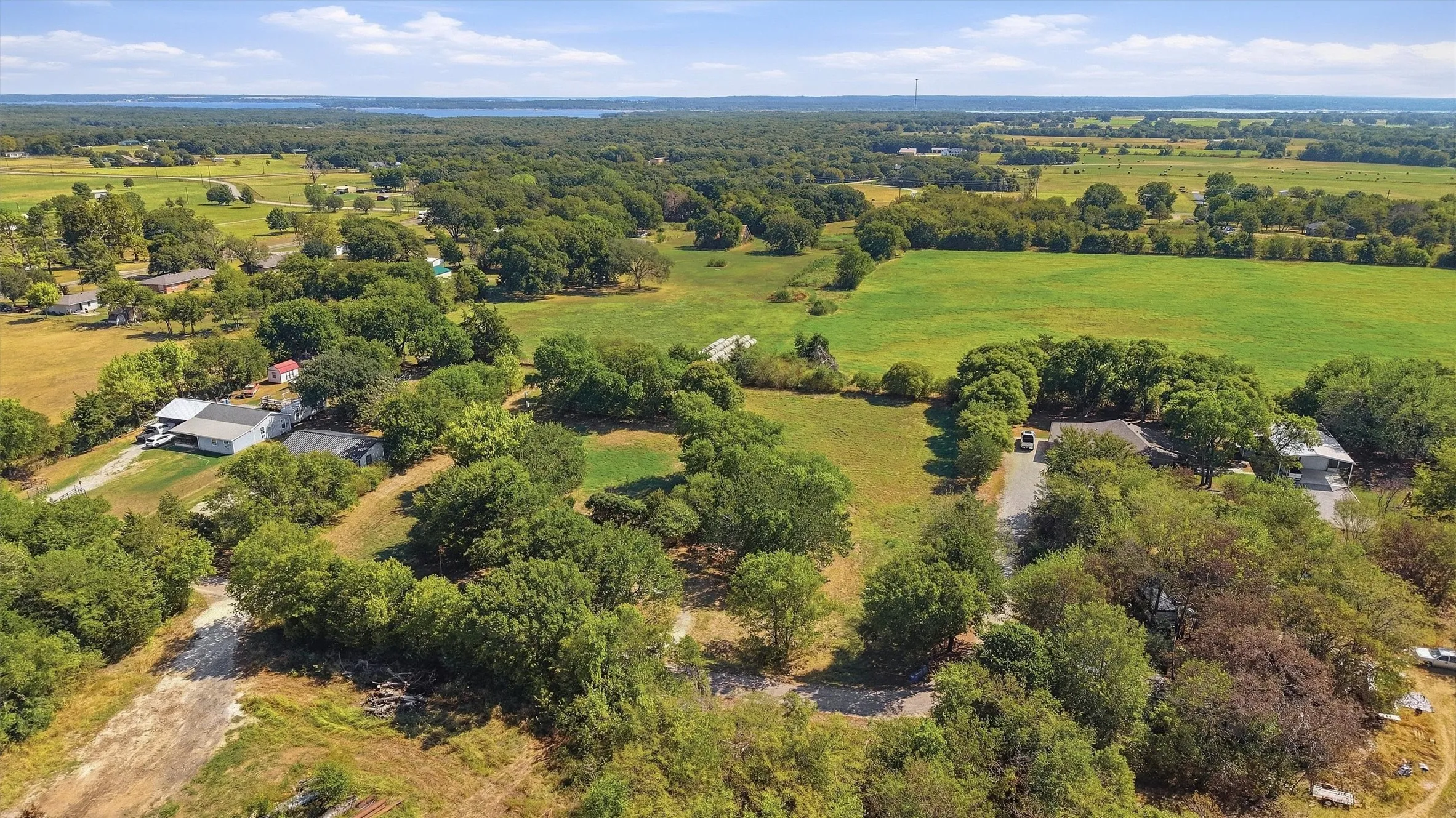 Expansive land featuring mature trees and a distant body of water