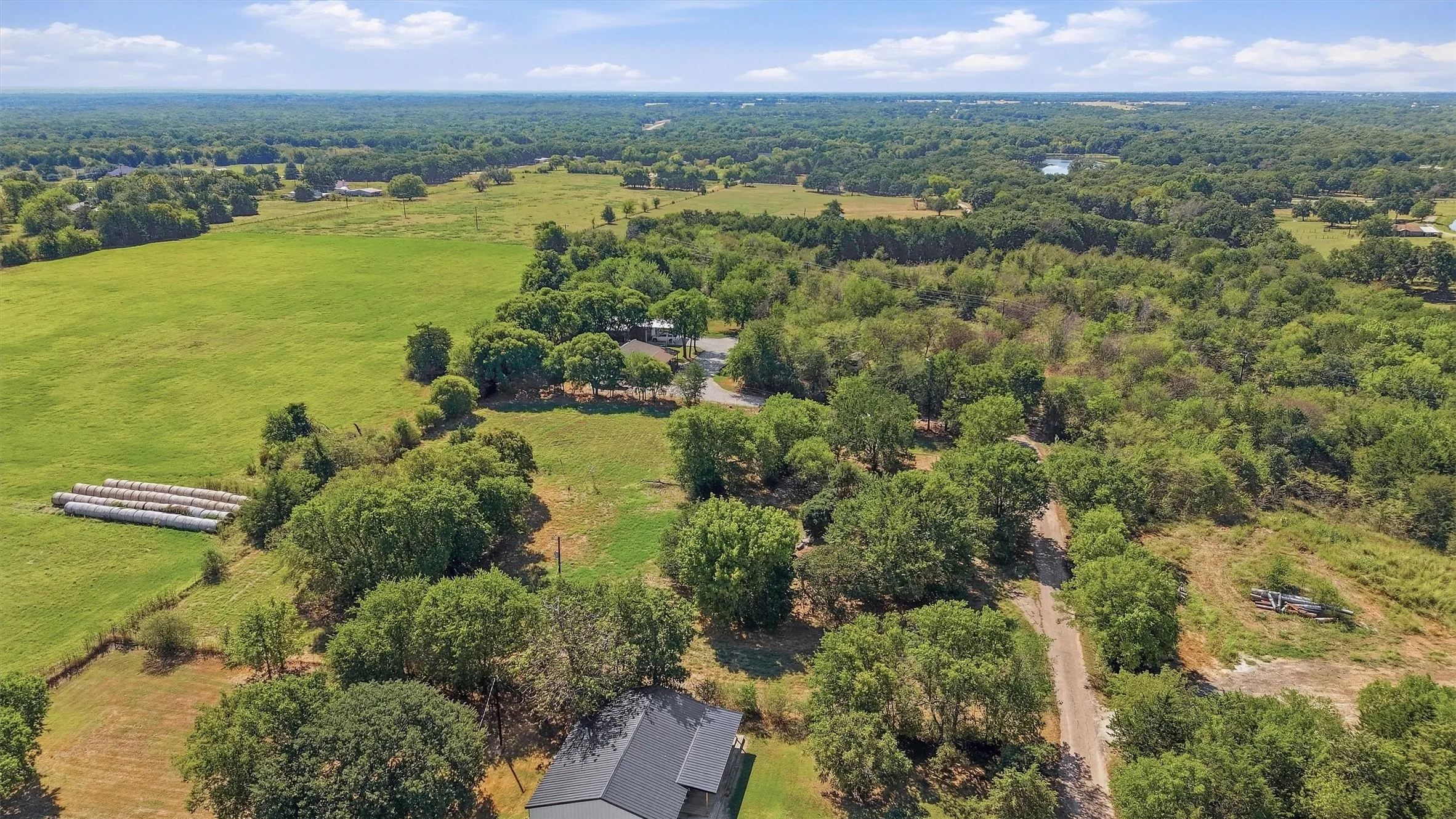 Expansive green fields, mature trees, and a distant body of water