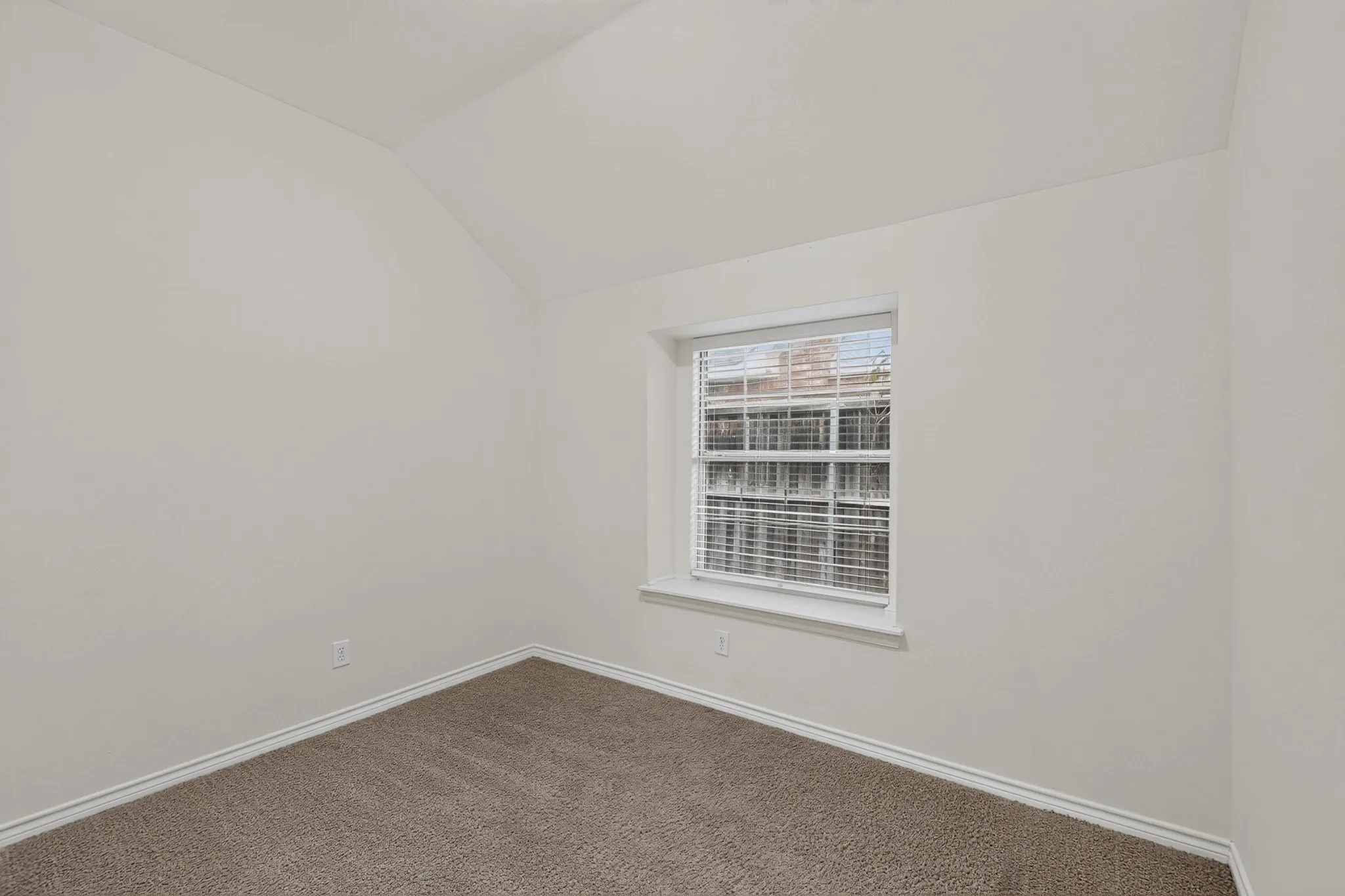 Neutral painted walls, carpeted flooring, and a single window with blinds