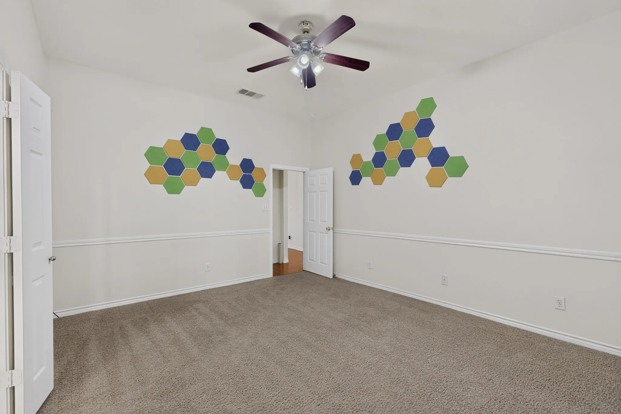 Carpeted flooring, vaulted ceiling, ceiling fan, white paneled doors, and wainscoting