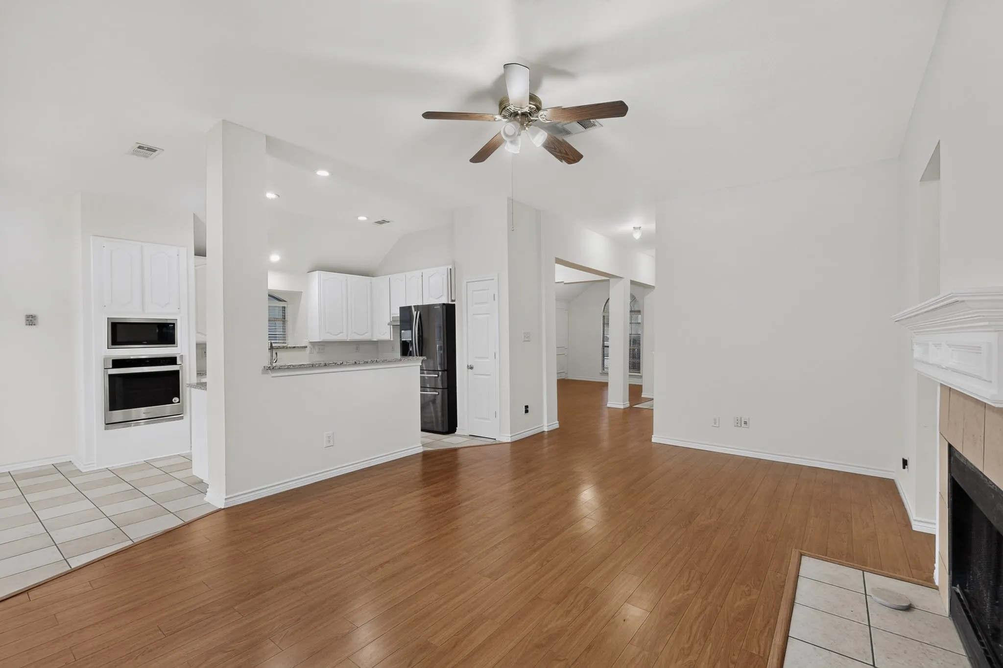 Wood-finish flooring, recessed lighting, and a fireplace with a decorative mantel